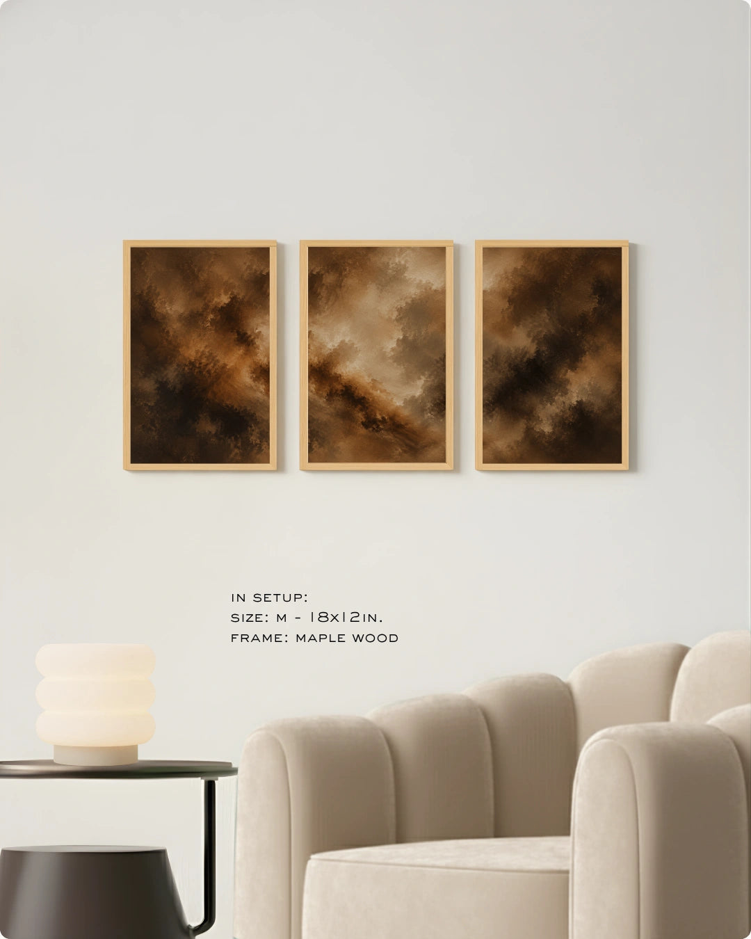 Three framed abstract wall art prints with warm brown and gold tones hang on a light gray wall above a cream sofa. Small text below reads 'IN SETUP: SIZE: M - 18x12 IN.