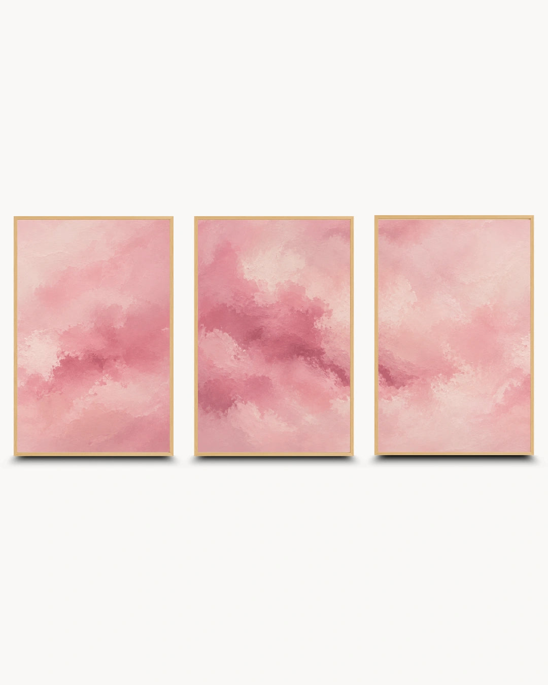 Three vertical framed wall art panels with soft pink watercolor-like abstract clouds, arranged side by side on a light gray background.