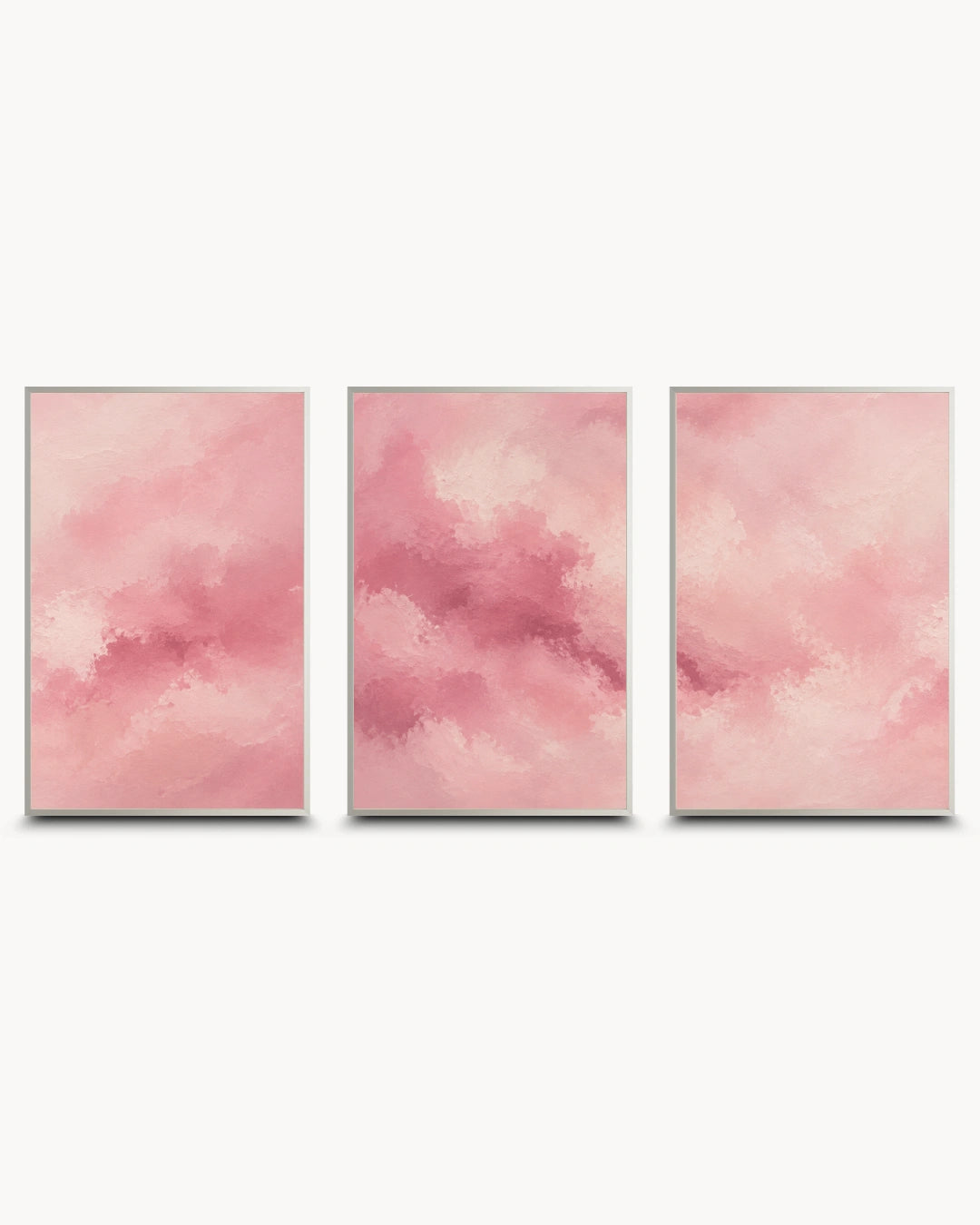 Three vertical framed wall art panels with soft pink watercolor-like abstract clouds, arranged side by side on a light gray background.