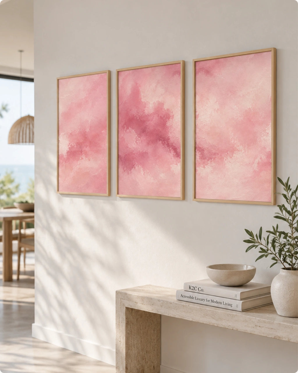 Three framed pink abstract wall art prints hang above a wooden bench in a bright, modern interior with plants and natural light.