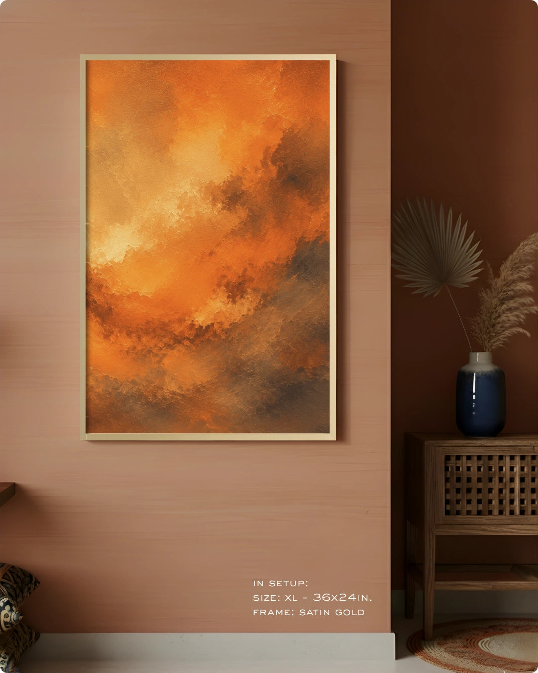 An abstract canvas wall art print featuring a dramatic orange and yellow sky with dark brown clouds, displayed in a gold frame on a warm terracotta wall in a styled interior setting.
