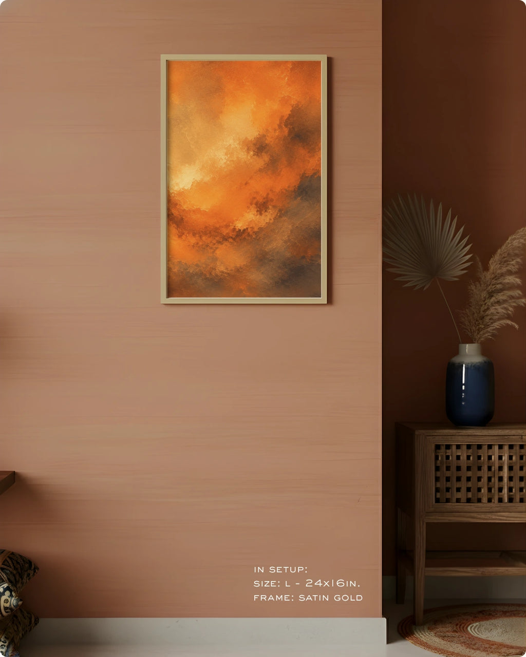 A framed abstract art print featuring vibrant orange and yellow cloud-like patterns, displayed on a warm peach-colored wall in a styled interior setting with a wooden side table and vase.