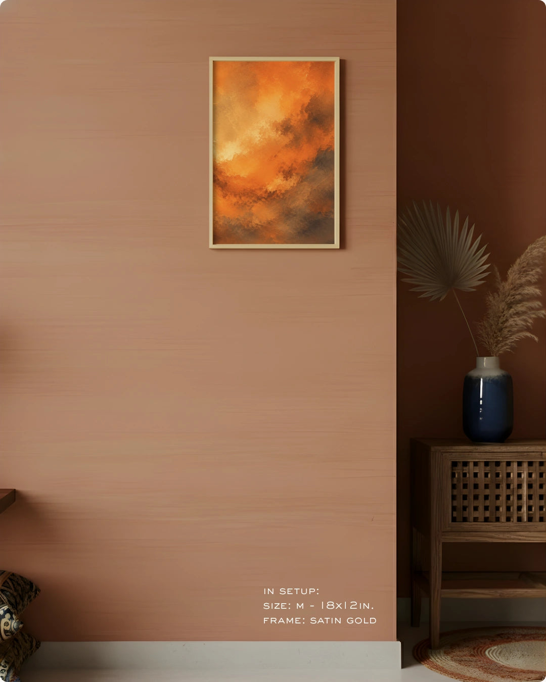 A framed abstract art print featuring vibrant orange and yellow clouds with dark brown undertones, hung on a textured terracotta wall in a styled interior setting.