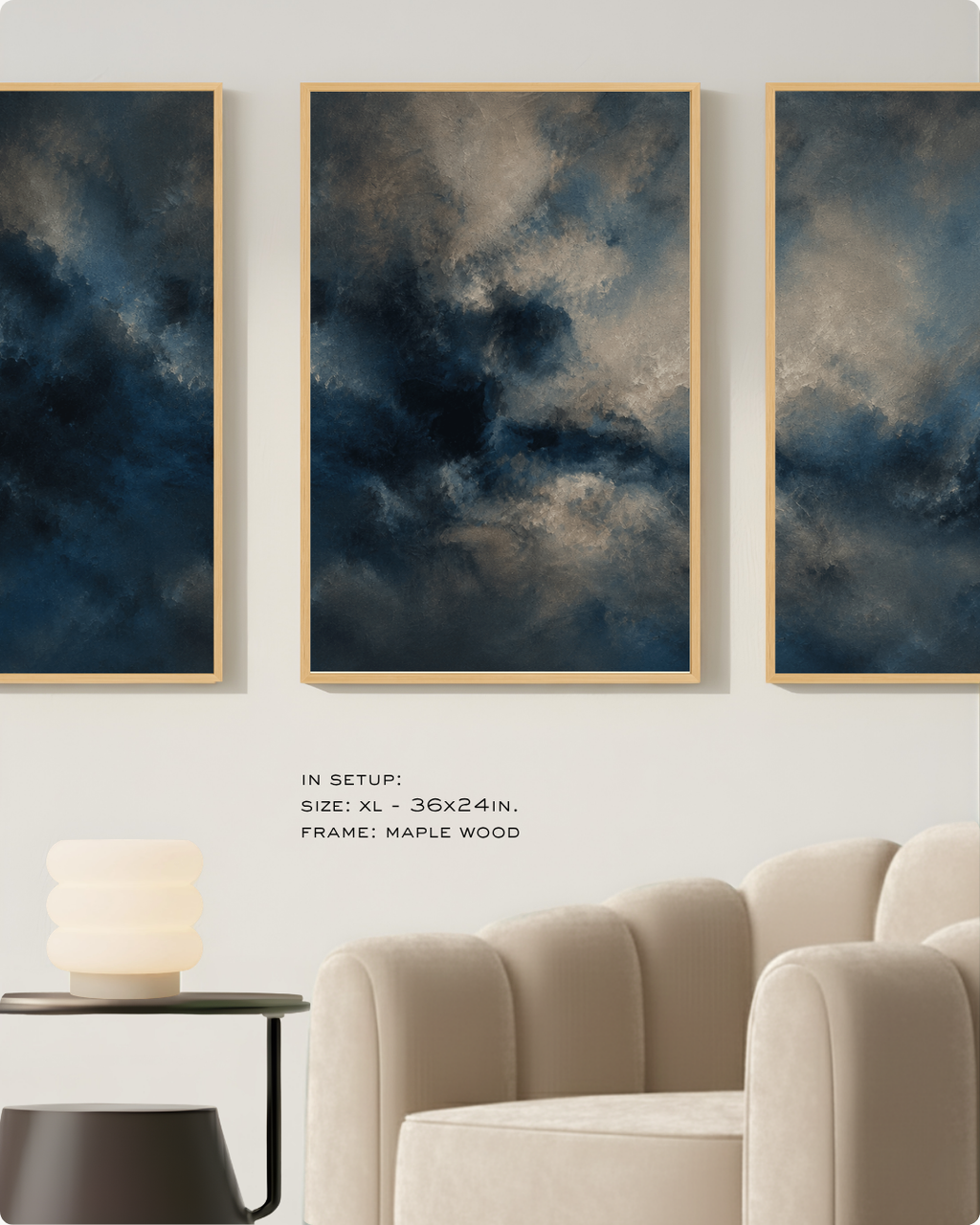 Three framed vertical wall art prints with a dark blue and gray cloudy sky design, displayed on a beige wall above a cream armchair and side table. Text below reads 'IN SETUP: SIZE: XL - 36x24in.
