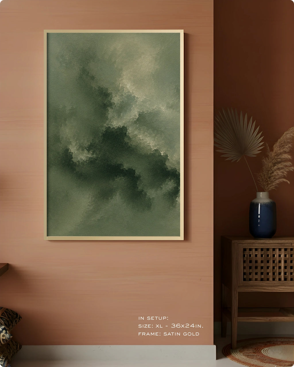A framed abstract wall art print hangs on a warm terracotta wall in a styled interior. The artwork features a textured, painterly composition in muted green and gray tones with a thin gold frame.