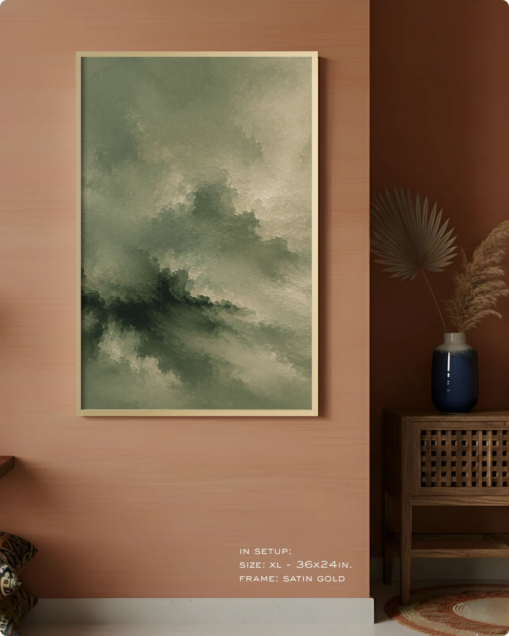 A framed abstract landscape art print featuring green and gray clouds, displayed on a warm terracotta wall in a styled interior setting with a wooden side table and vase.