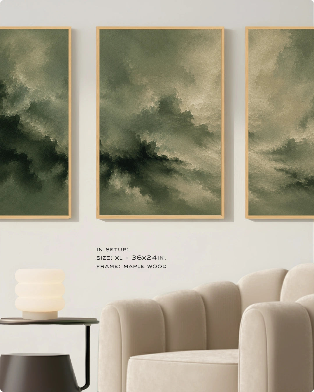 Three vertical framed wall art prints with abstract green and beige cloudy designs, displayed above a cream sofa in a styled interior setting. Text below reads: 'IN SETUP: XL - 36x24in, FRAME: MAPLE WOOD'.