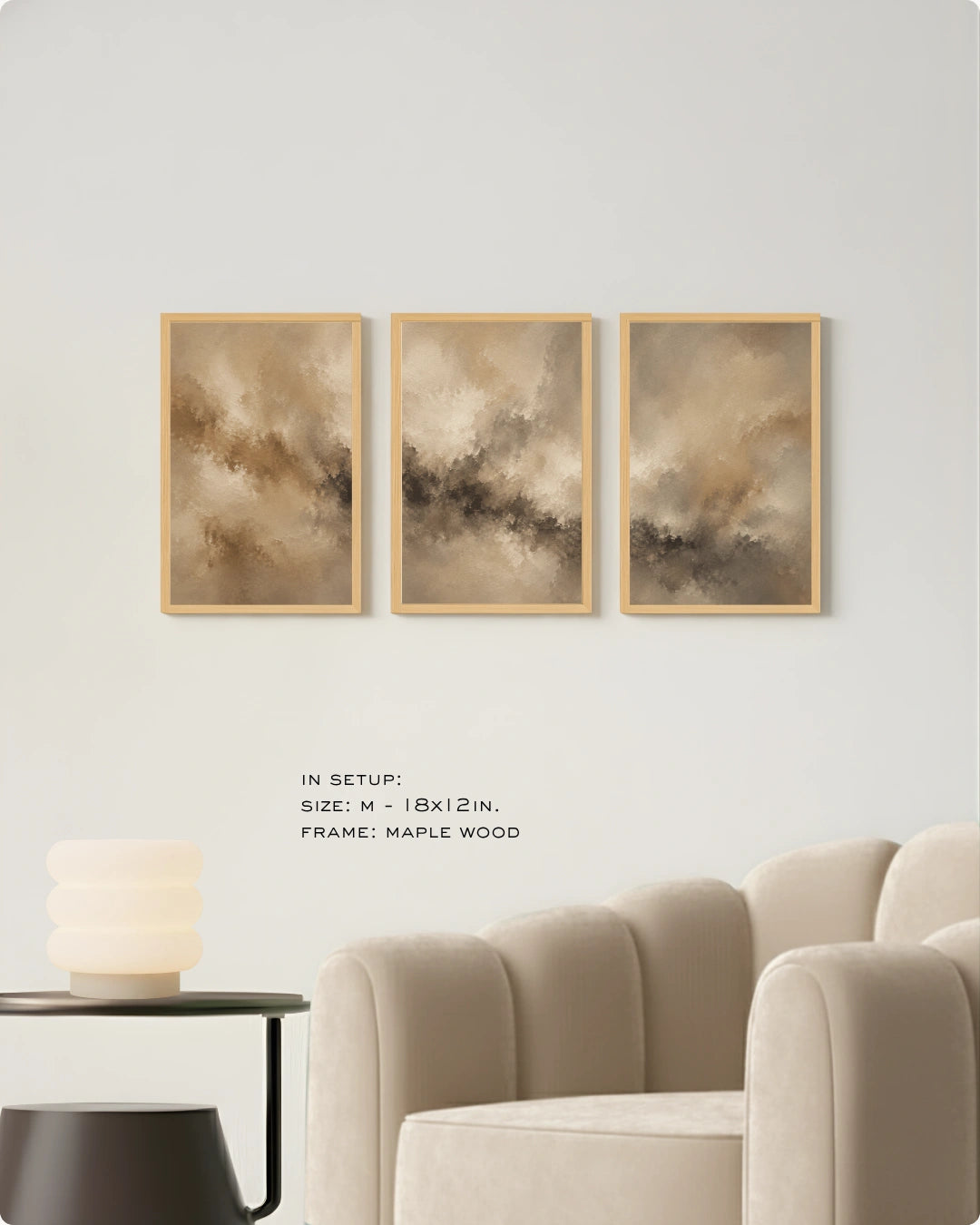 Three framed abstract wall art prints in warm beige, brown, and gray tones hang on a light gray wall above a cream sofa, with small text noting size and maple wood frame.