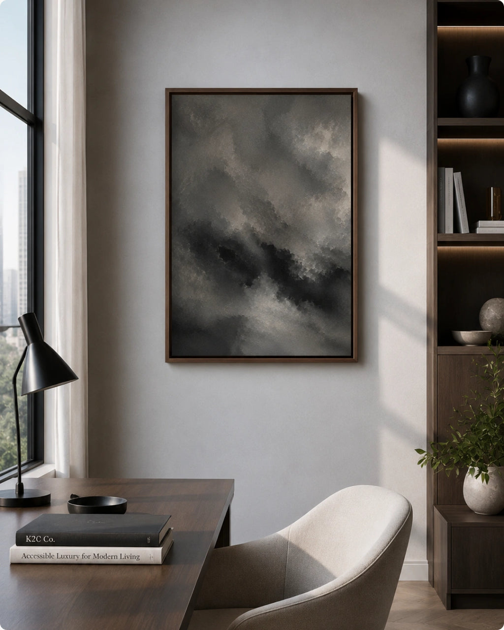 A framed dark stormy landscape painting hangs on a light gray wall in a modern home office setting with a desk, chair, and bookshelf.