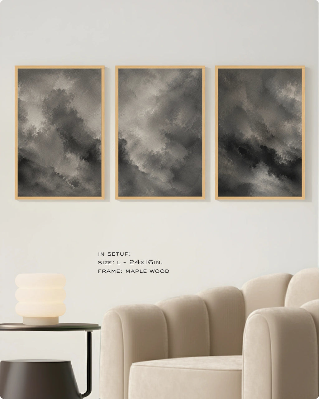 Three framed black and white cloud art prints displayed on a light beige wall above a cream-colored armchair, with a small side table and lamp in the foreground. Text on the wall reads 'IN SETUP: SIZE: L - 24x16IN.