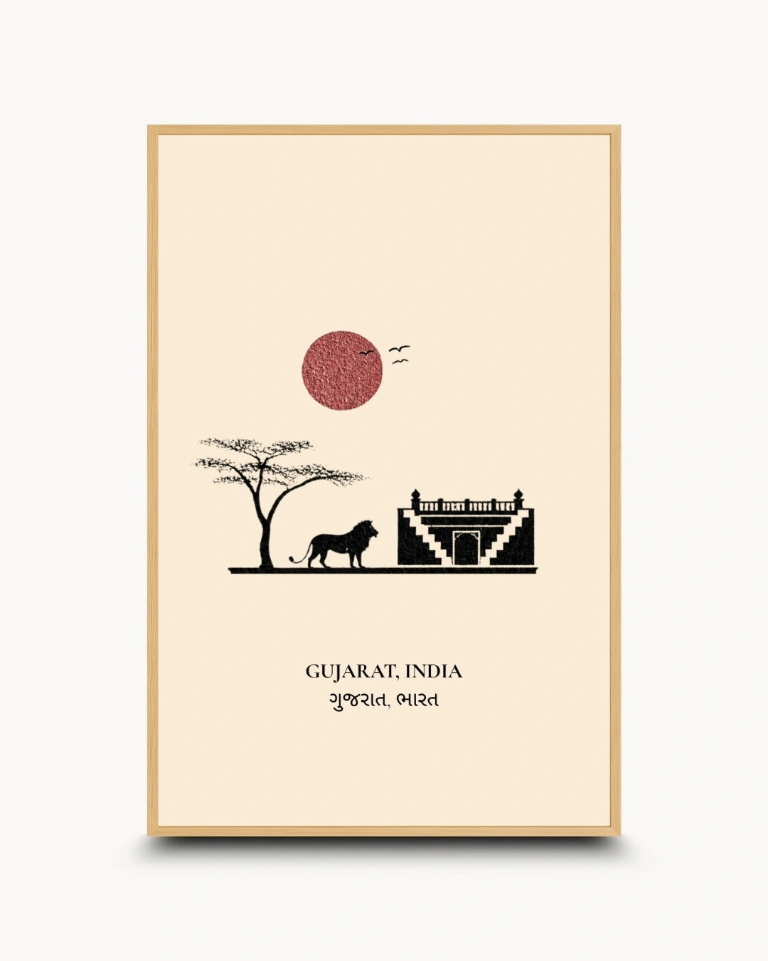 A framed art print featuring a minimalist illustration of Gujarat, India, with a lion, tree, fort, and red sun on a cream background, enclosed in a light wood frame.