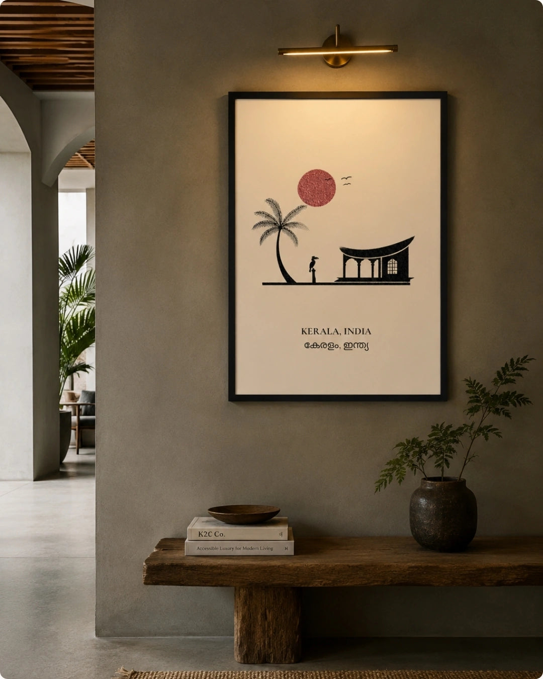 A framed minimalist art print of Kerala, India, hanging on a textured gray wall in a modern interior setting with a wooden bench and potted plants below.