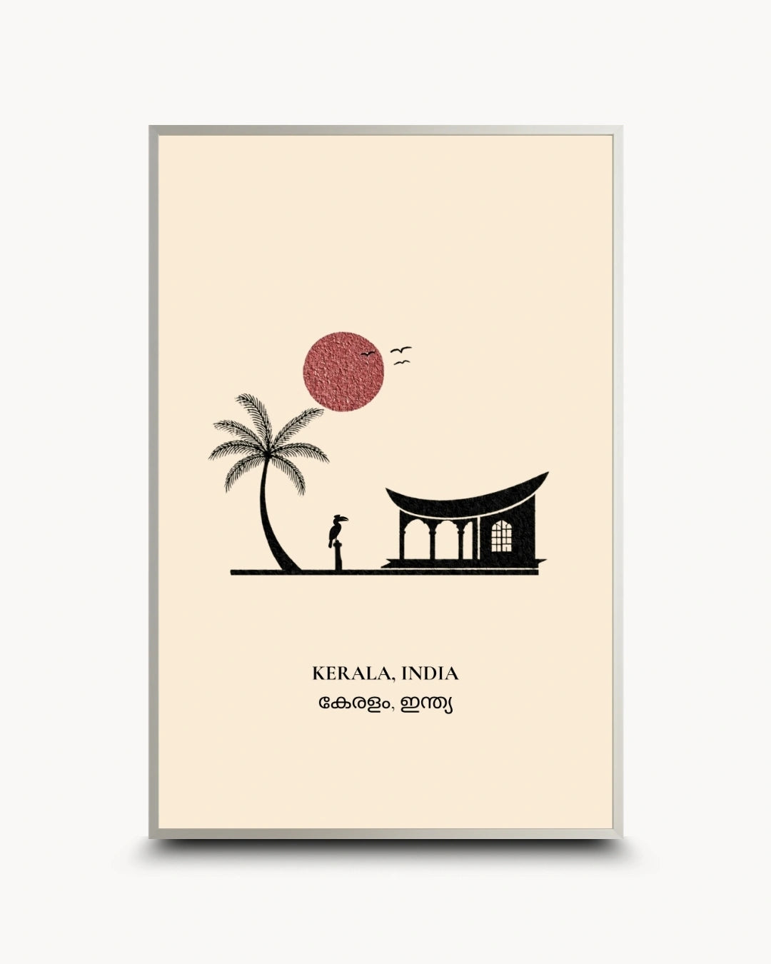 A framed art print featuring a minimalist illustration of Kerala, India. The print has a cream background with a black silhouette of a palm tree, a traditional house, and a person, alongside a textured red-pink sun and the text 'KERALA, INDIA' with Malayalam script below.