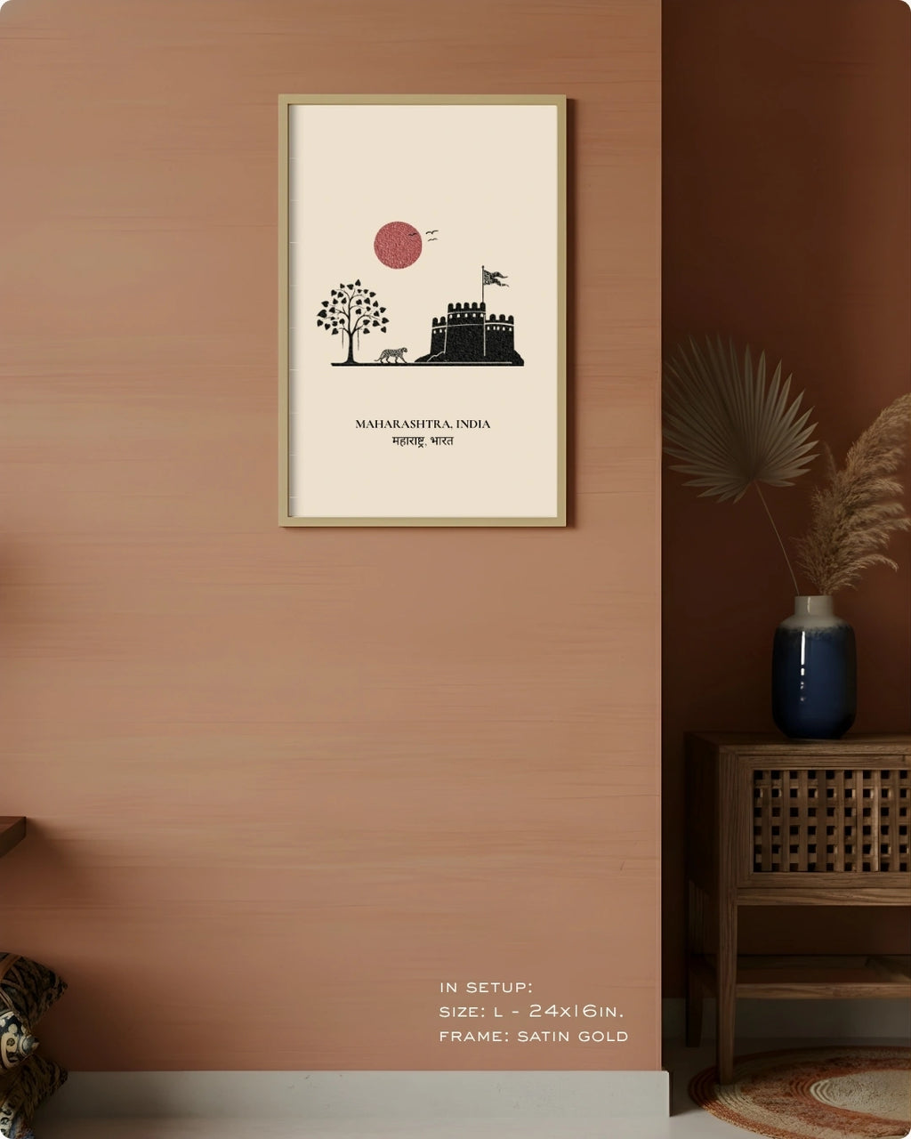 A framed minimalist art print of Mahashashtra, India, hanging on a warm terracotta-colored wall in a styled interior setting with a wooden cabinet and dried palm leaves.