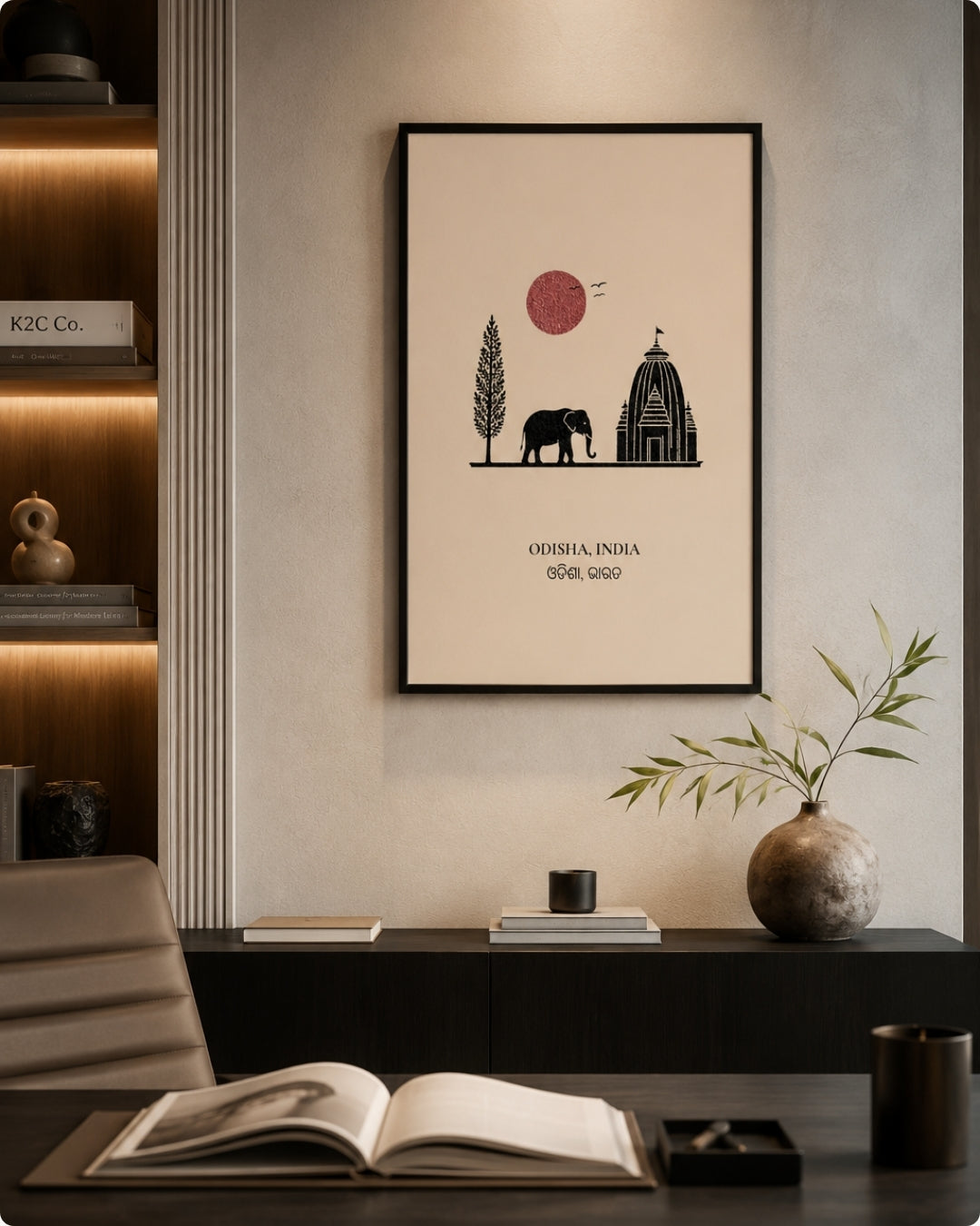 A framed minimalist art print featuring an elephant, a tree, a dome-shaped building, and a red sun on a cream background, hanging on a wall above a dark console table in a styled interior setting.