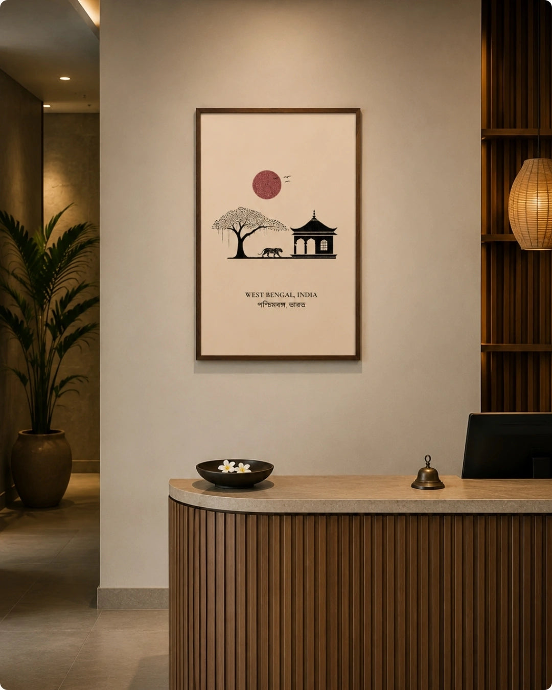 A framed minimalist art print featuring a red sun, a tree, and a pagoda with the text 'WEST METROPOLIS, INDIA' hanging on a beige wall above a wooden reception desk in a modern lobby.