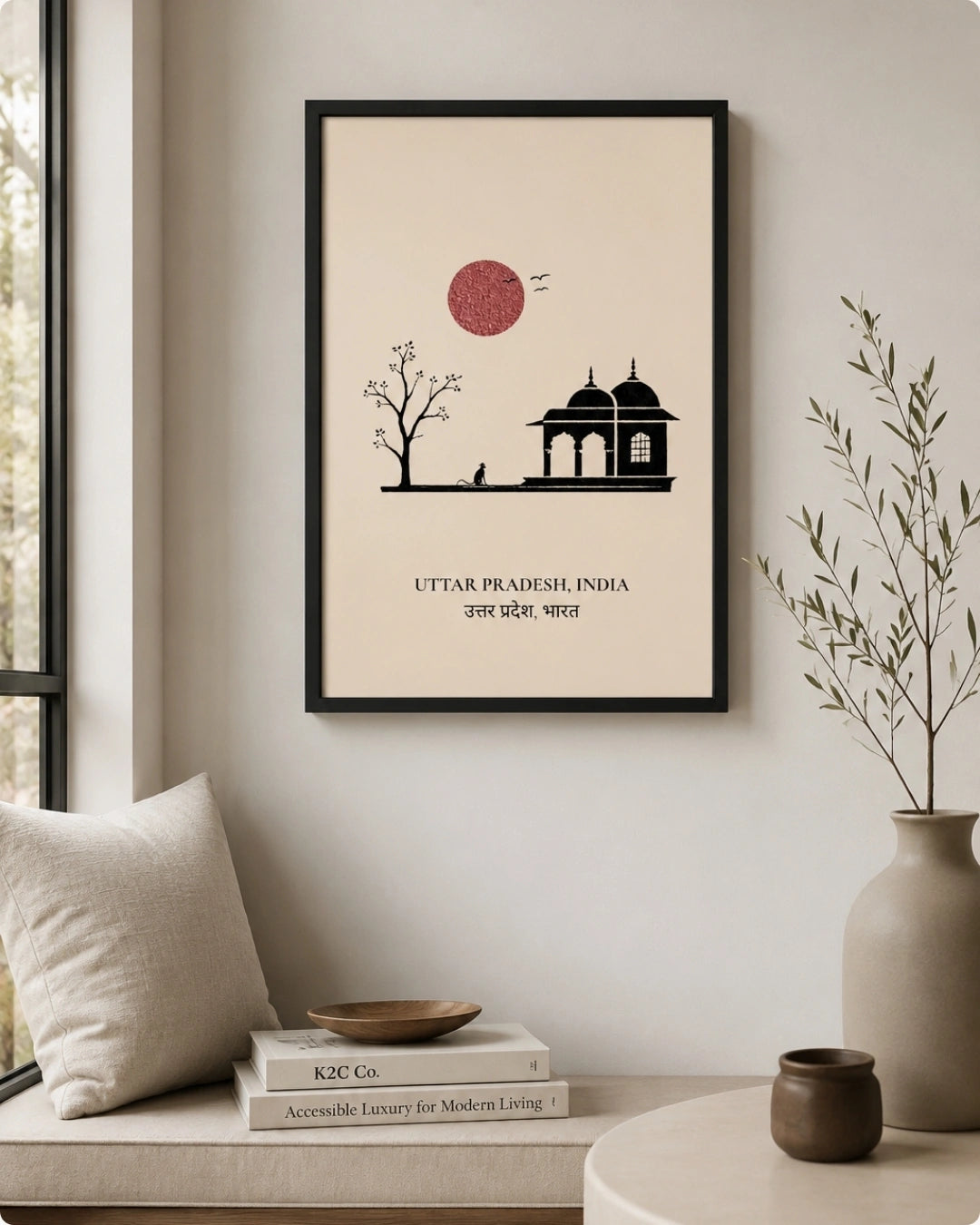 A framed minimalist art print of Uttar Pradesh, India, hanging on a light beige wall in a styled room setting with a window, pillow, books, and a vase.