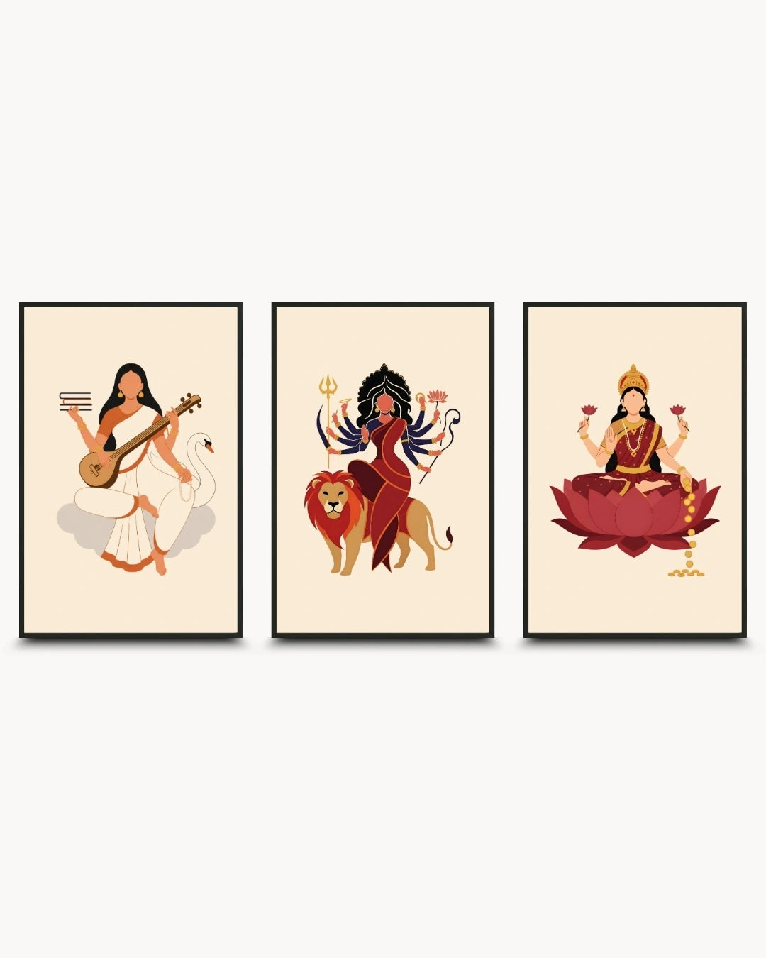 A set of three framed wall art prints featuring stylized illustrations of Hindu goddesses: Sarawati, Durga, and Lakshmi. The prints have a warm cream background and are arranged side by side against a light gray wall.
