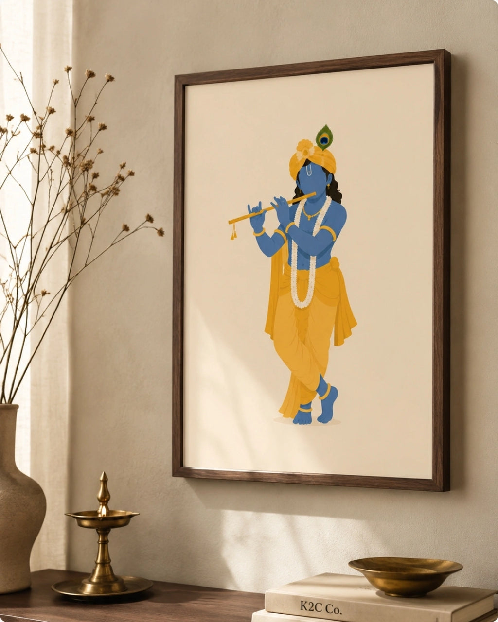 A framed art print of a stylized ISKON Krishna in yellow and blue, hanging on a beige wall above a wooden table with a brass lamp, vase, and books.