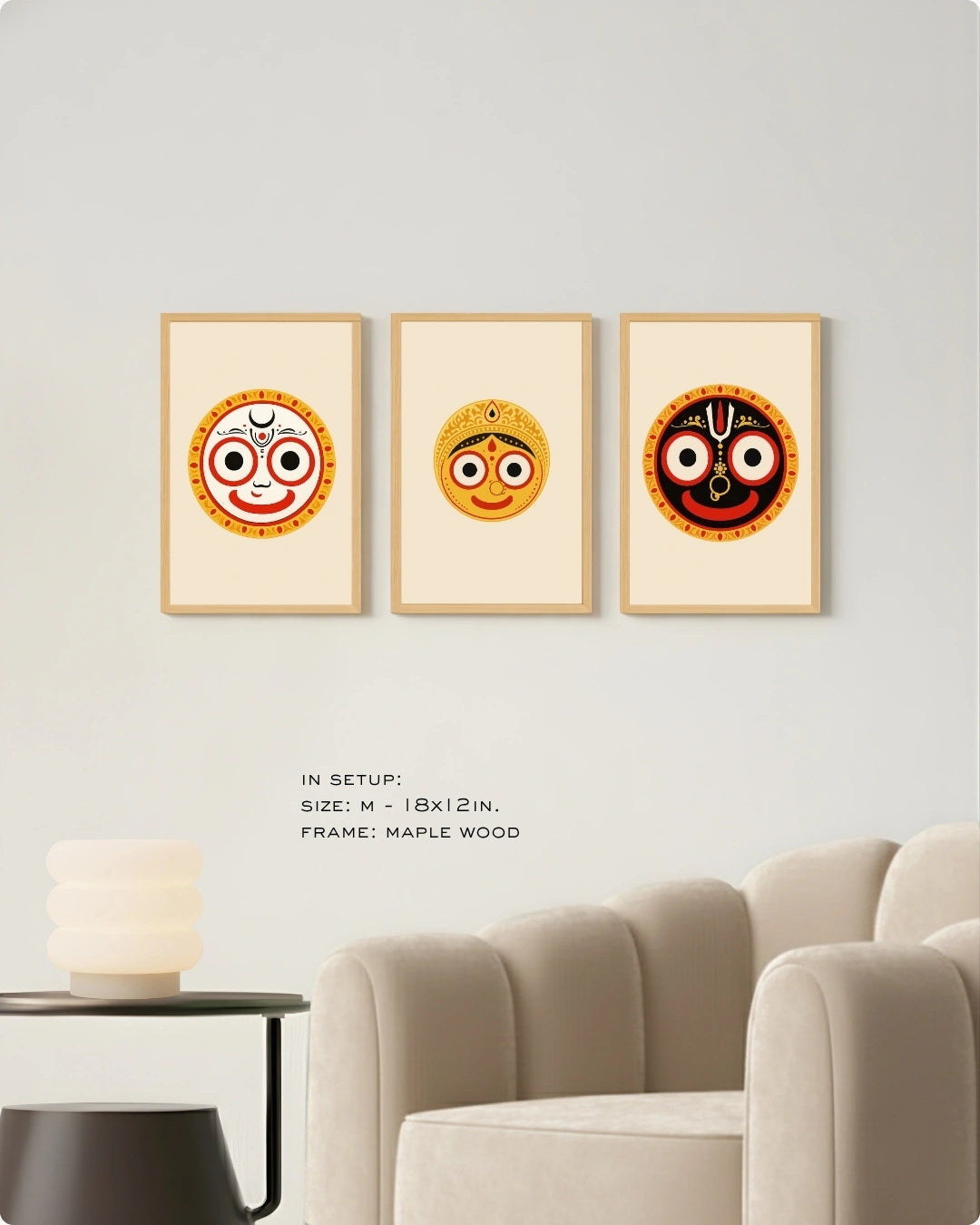 Visual size guide mockup for the Jagannath Triad 3-piece wall art set in Medium size with satin gold frames, displayed above a modern ribbed beige armchair.
