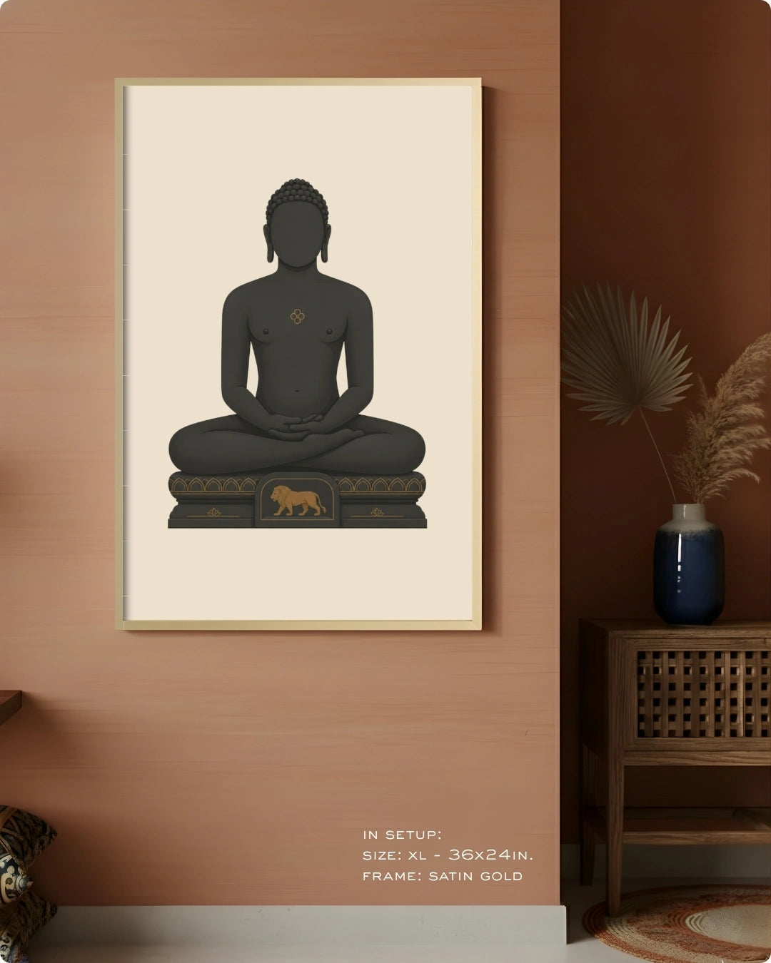 A framed wall art print featuring a seated Mahavira figure in dark charcoal gray on a warm cream background, hung on a terracotta-colored wall in a styled interior with a wooden side table, blue vase, and dried palm leaves.