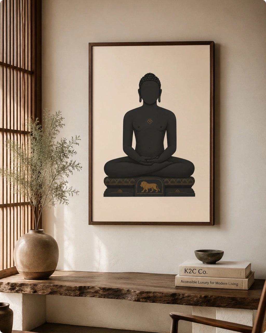A framed wall art print featuring a seated Mahavira silhouette in dark charcoal on a warm cream background, hung above a wooden console table in a styled interior with a vase, books, and a bowl.