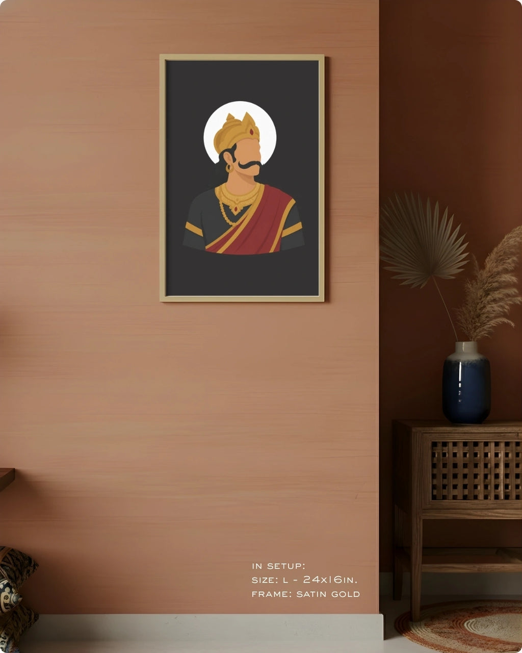 A framed art print featuring a stylized illustration of Raavana with a gold crown and red drape on a dark background, displayed on a warm peach-colored wall in a styled interior setting.