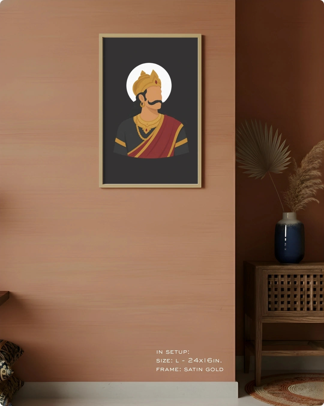 A framed art print featuring a stylized illustration of Raavana with a gold crown and red drape on a dark background, displayed on a warm peach-colored wall in a styled interior setting.