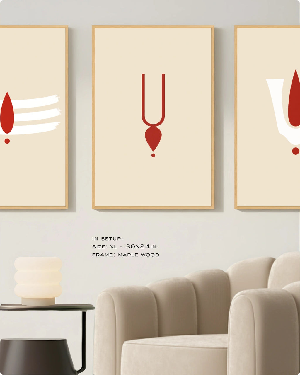 Three framed minimalist wall art prints hang above a beige armchair in a styled interior. Each print has a cream background with a red abstract symbol and a light wood frame.