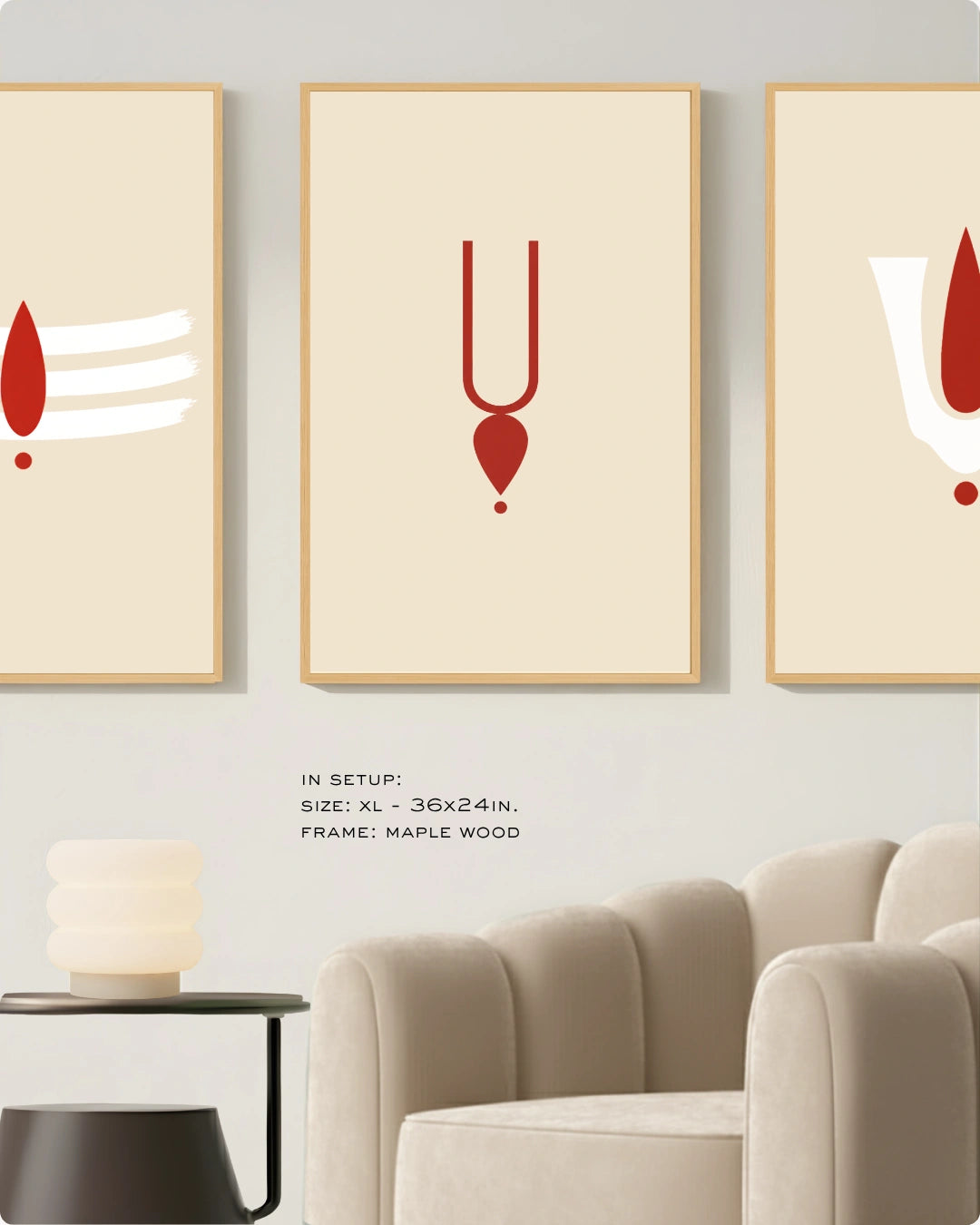 Three framed minimalist wall art prints hang above a beige armchair in a styled interior. Each print has a cream background with a red abstract symbol and a light wood frame.