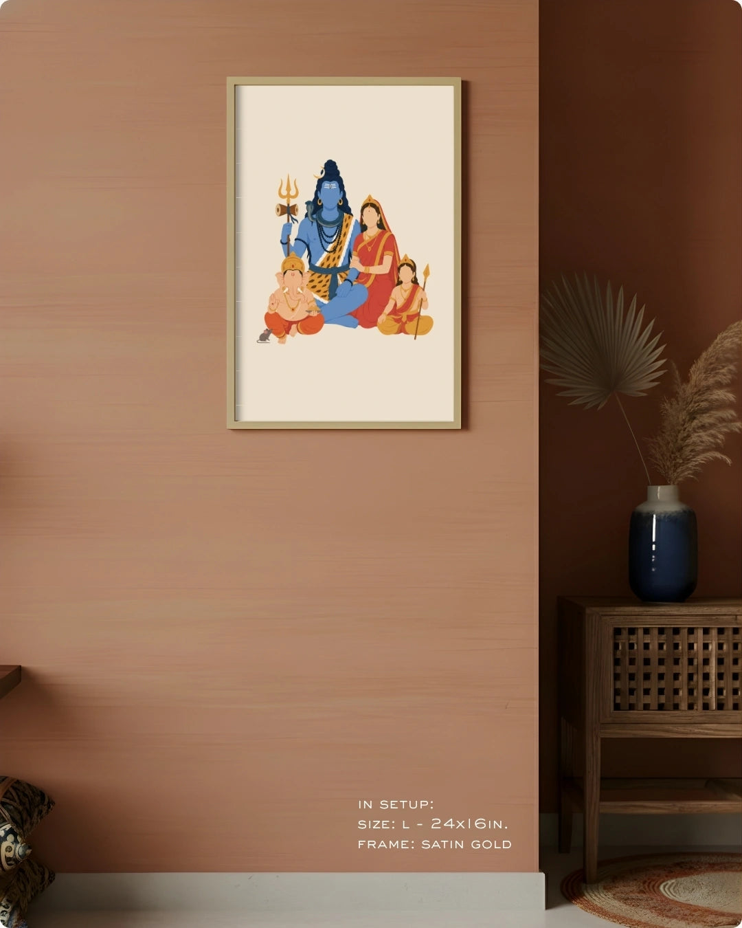 A framed art print depicting the Hindu family of Krishna, styled on a textured terracotta wall in a home decor setting next to a wooden side table and vase.