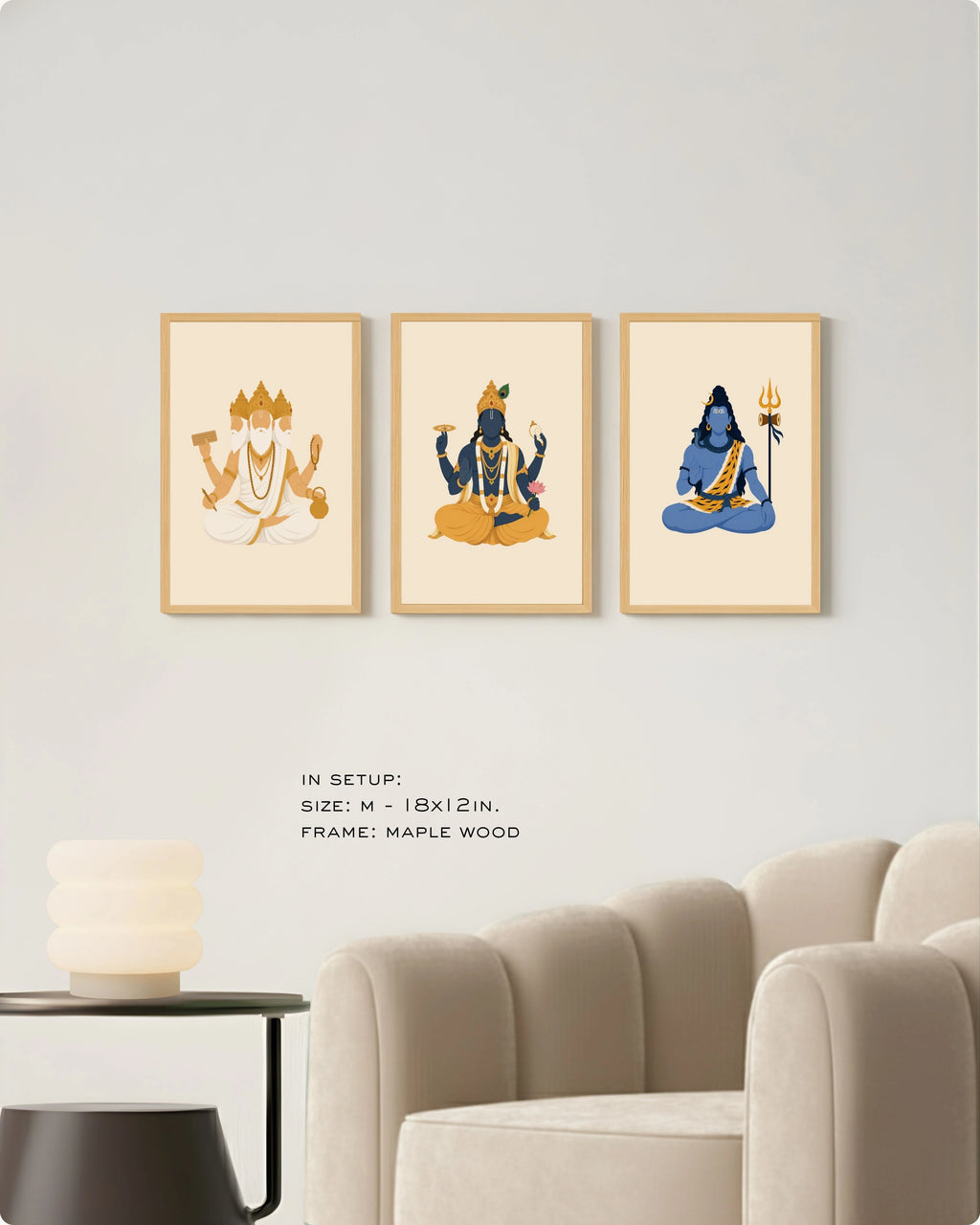 Visual size guide mockup for the Hindu Trimurti wall art set of 3 in size Medium (18x12 inches) with maple wood frames, shown scaled perfectly next to a contemporary beige armchair.