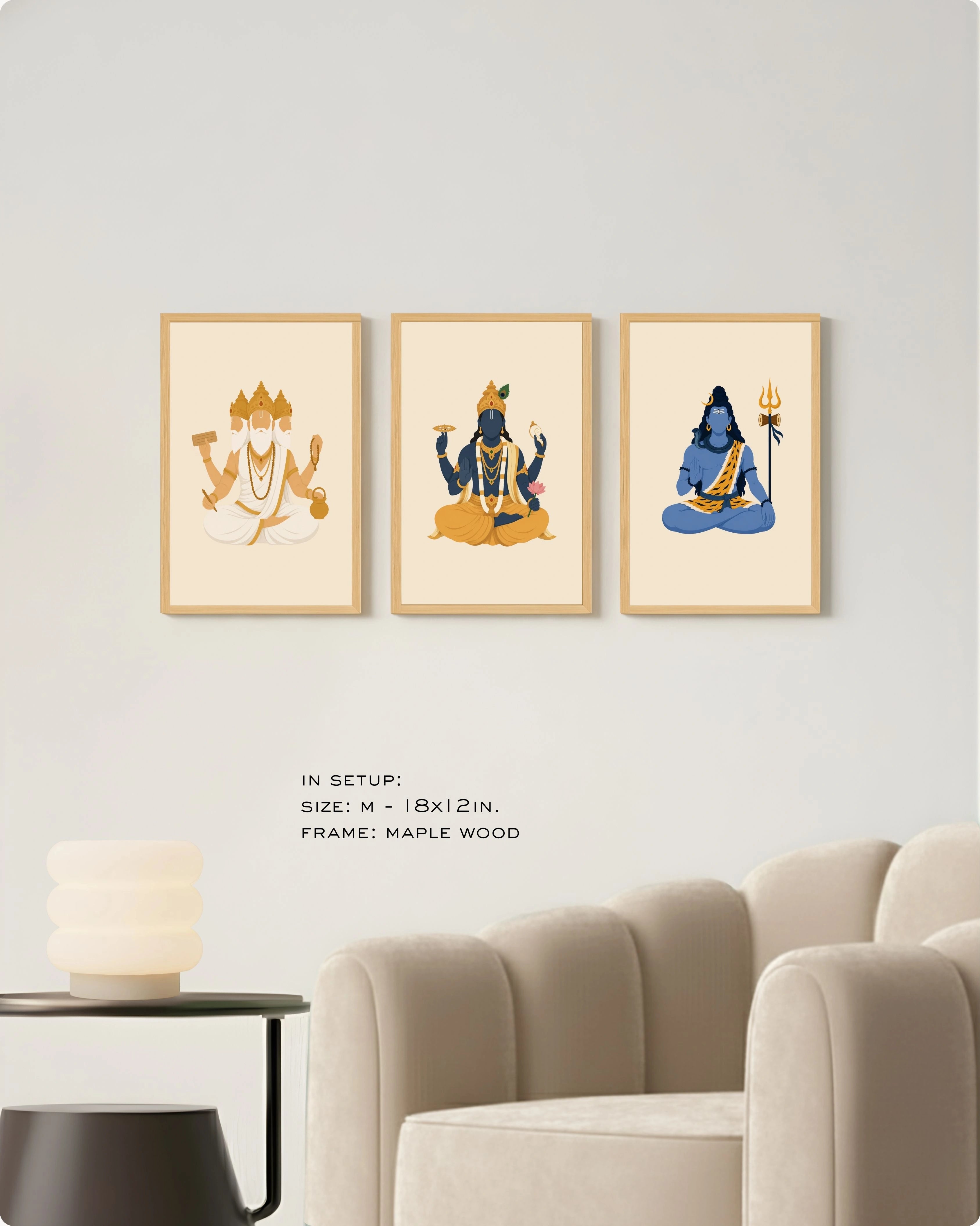 Visual size guide mockup for the Hindu Trimurti wall art set of 3 in size Medium (18x12 inches) with maple wood frames, shown scaled perfectly next to a contemporary beige armchair.
