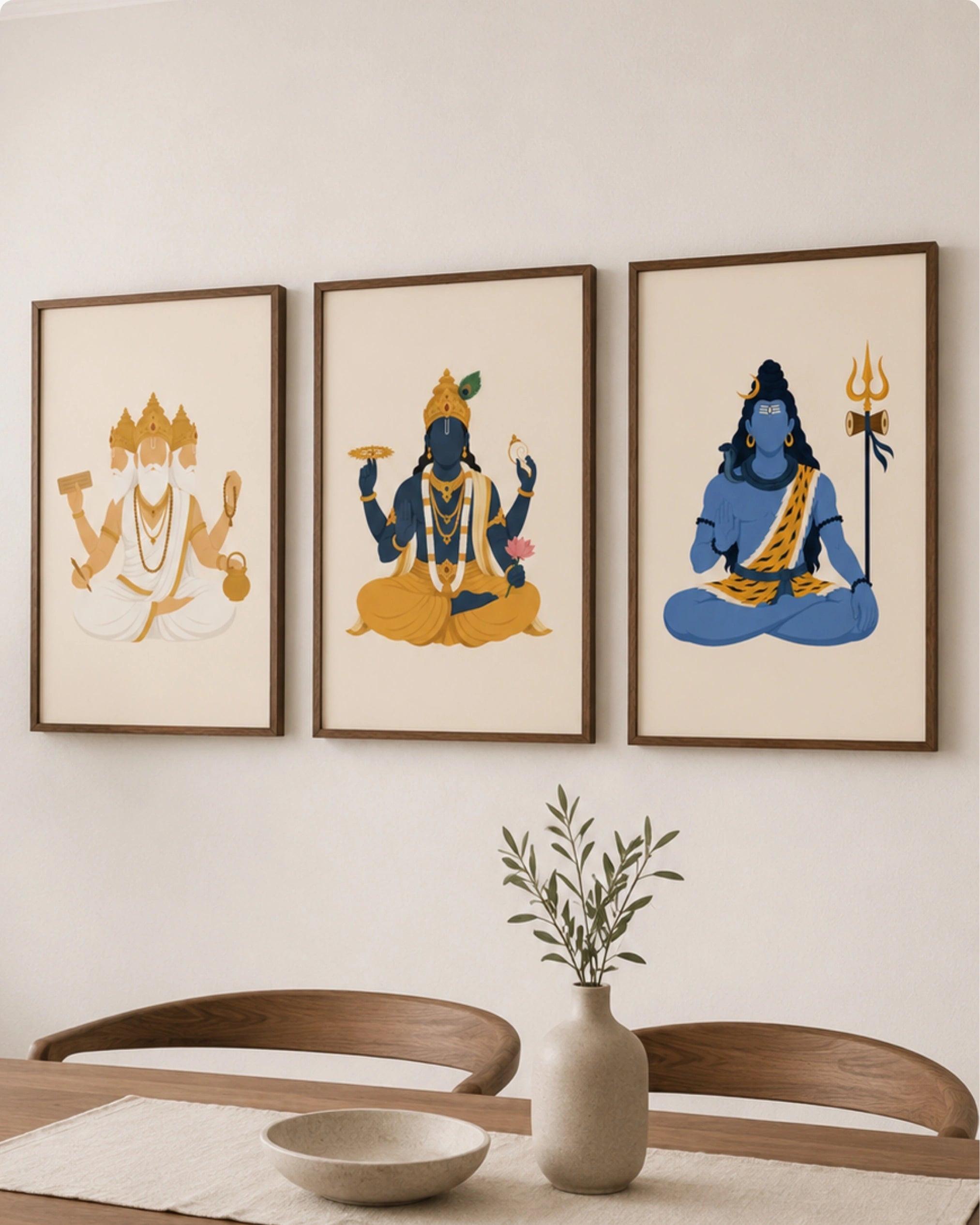 Lifestyle interior mockup of the Hindu Trimurti wall art set of 3, featuring Brahma, Vishnu, and Shiva in size Large (24x16 inches) with walnut wood frames, hung above a minimalist wooden dining room table.