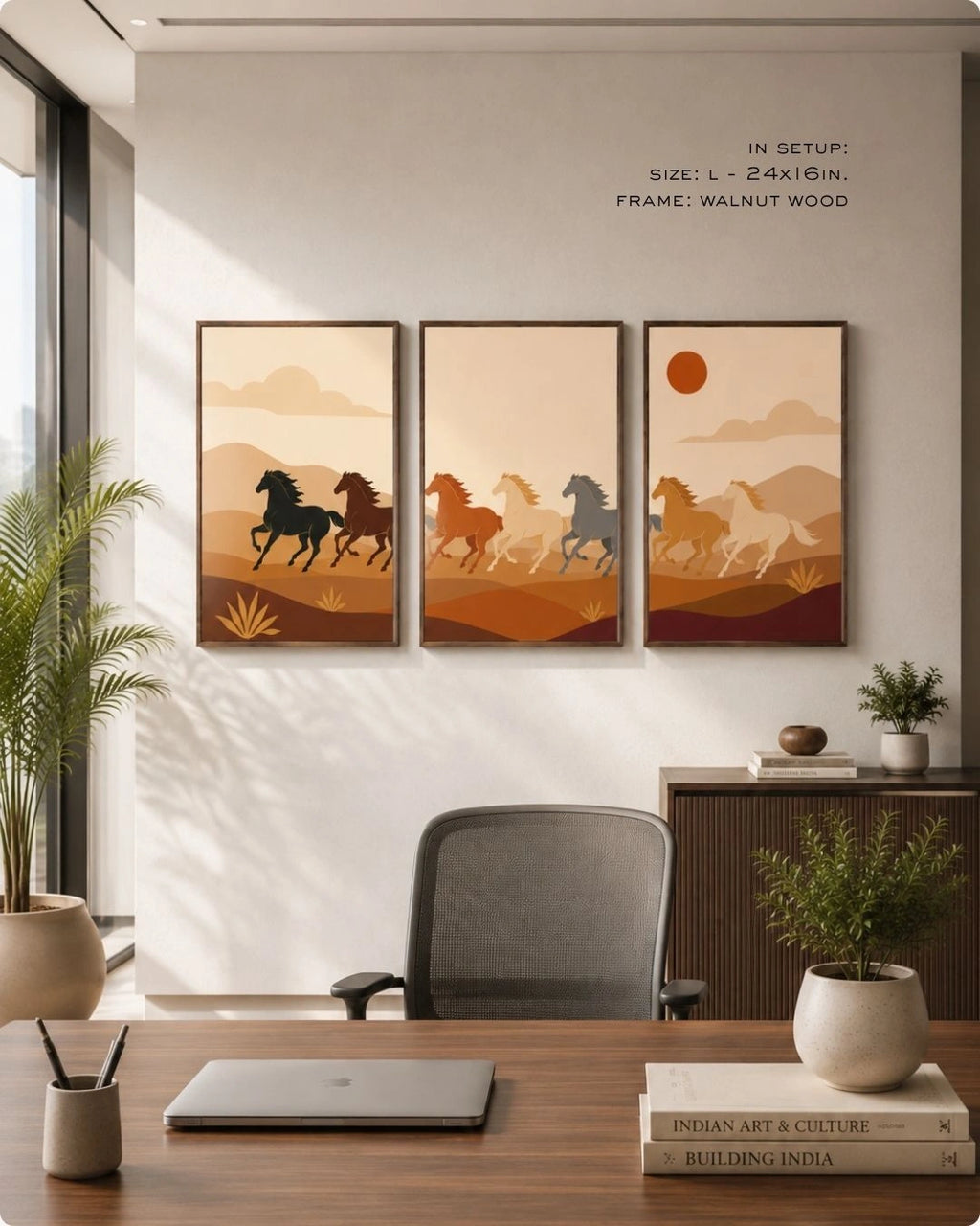 A set of three dark wood-framed wall art prints hanging in a modern, sunlit home office. The triptych features minimalist stylized horses running through an earth-toned desert landscape. In the foreground is a wooden desk with a modern grey office chair, a laptop, stacked books, and potted plants.