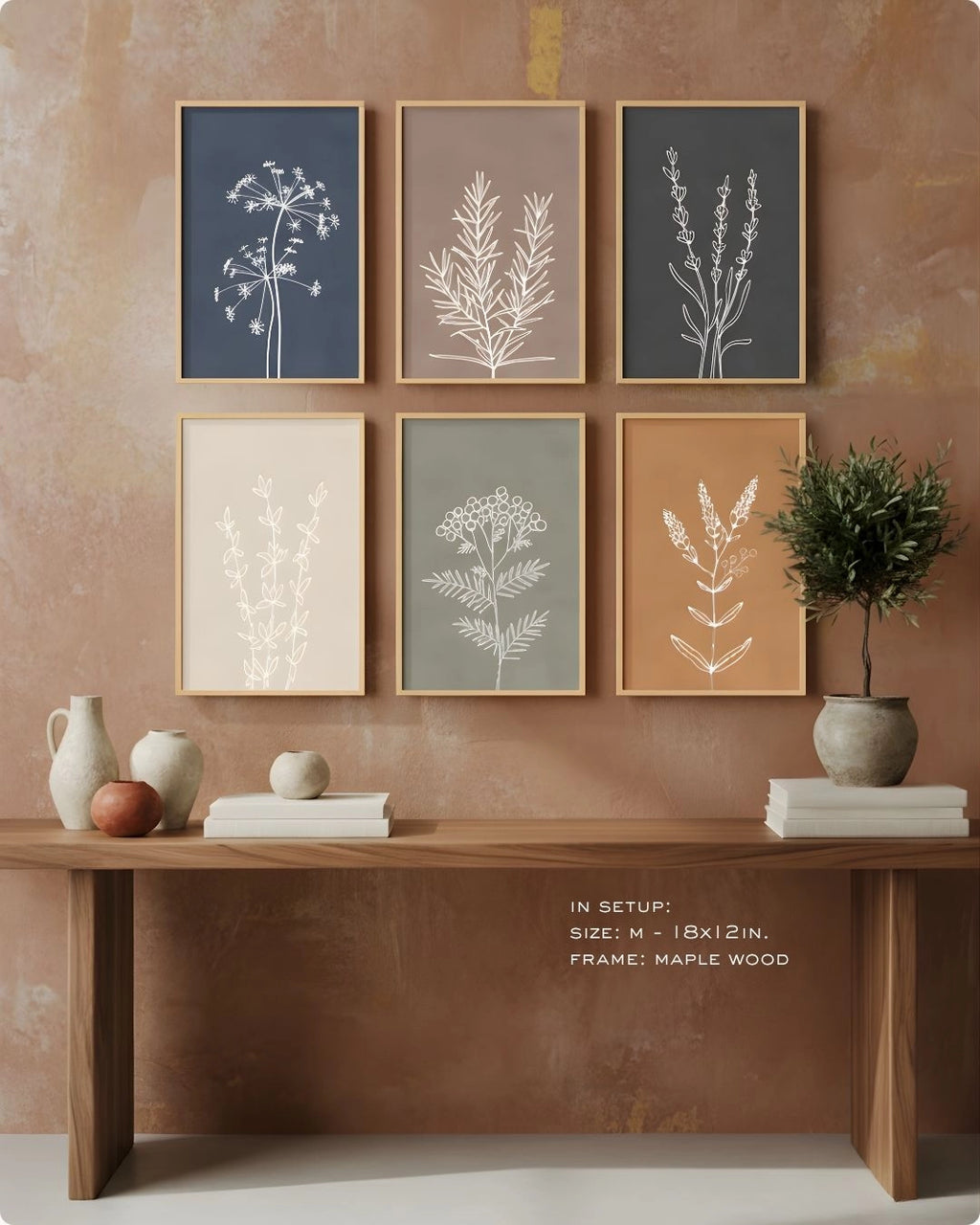 K2C Co. 6-piece Essence botanical gallery wall in Maple Wood frames. Features a cohesive earth-tone palette of sage, terracotta, and indigo on a warm neutral wall.