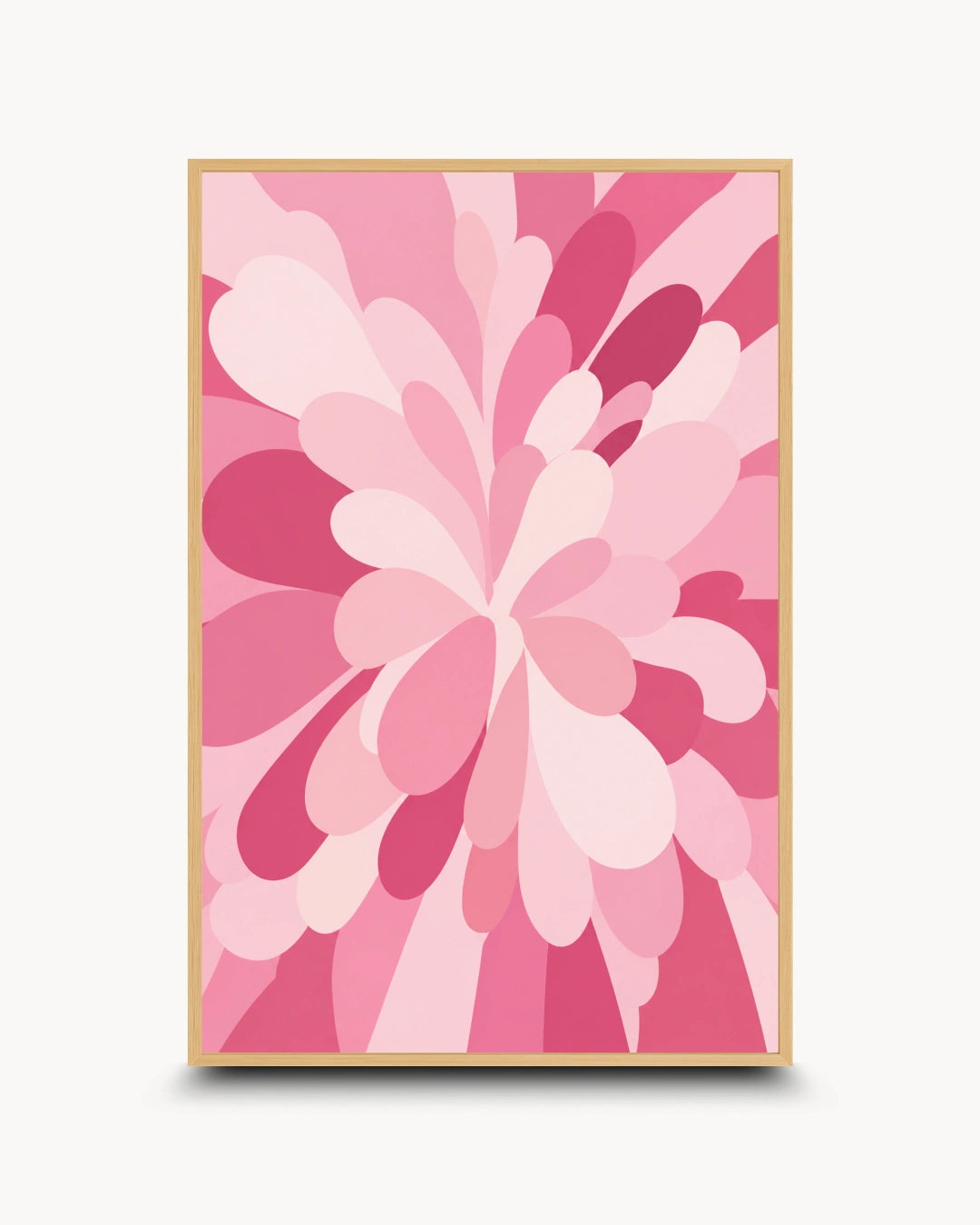 A framed abstract floral art print featuring layered petal-like shapes in various shades of pink, with a light wood frame, shown against a clean off-white background.