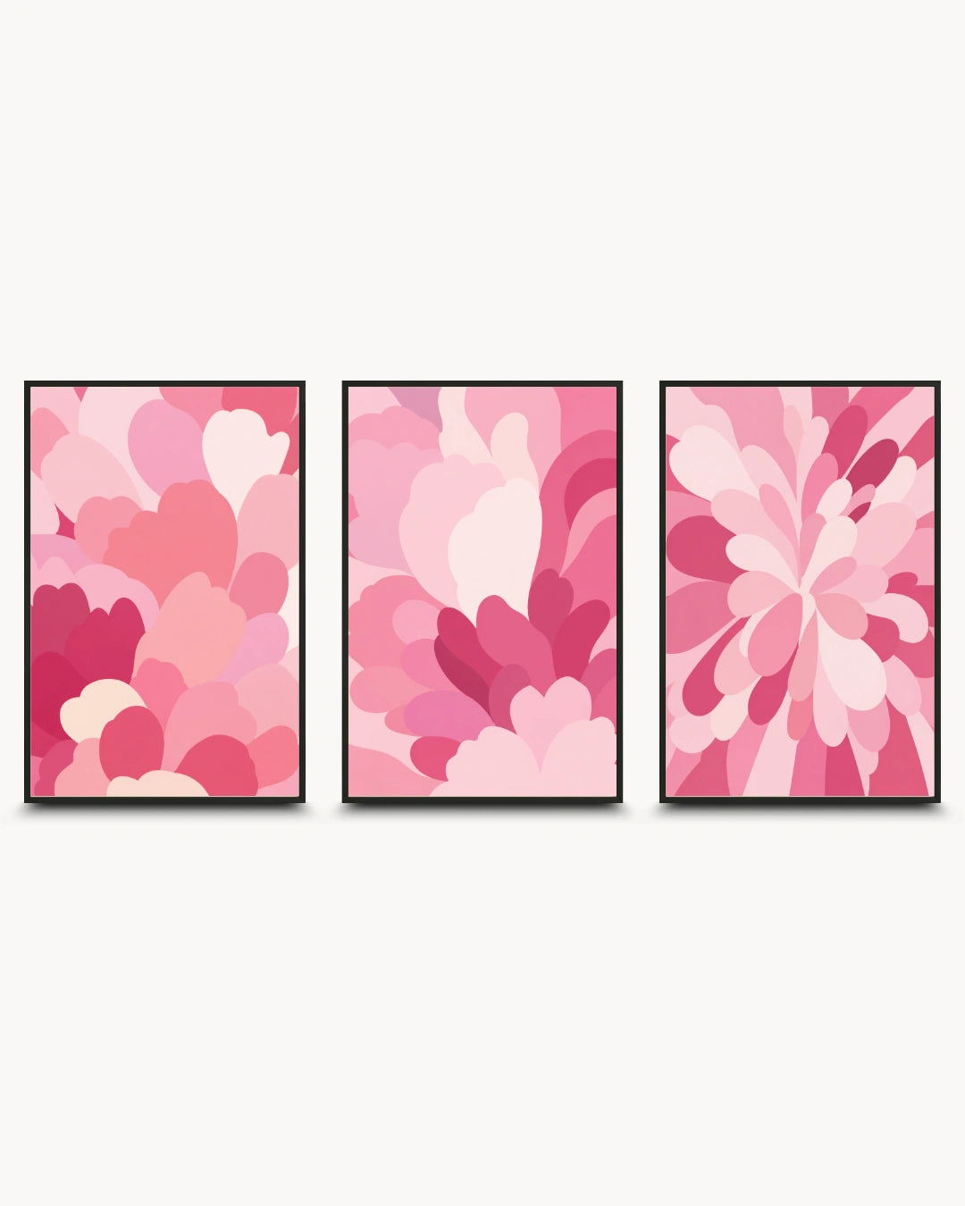 A three-piece framed wall art set featuring abstract floral and petal-like patterns in various shades of pink, with thin black frames, displayed against a light off-white background.