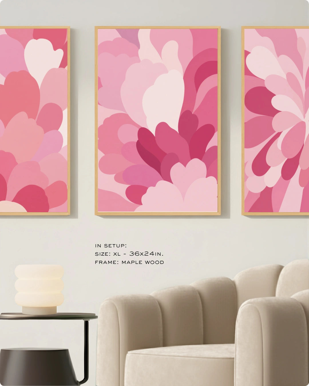 Three vertical framed wall art prints with abstract layered floral shapes in pink, magenta, and white tones, displayed above a beige armchair in a styled interior. Small text reads: 'IN SETUP: SIZE: XL - 36x24in.