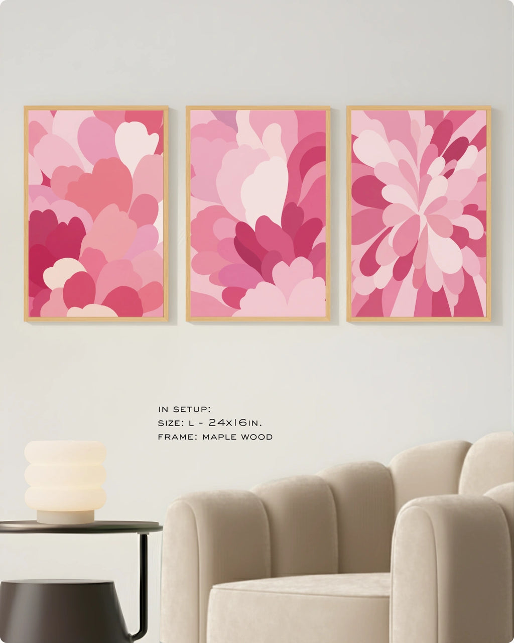 Three framed abstract floral wall art prints in shades of pink and magenta hang on a light wall above a beige armchair, with small text noting the size and maple wood frame.