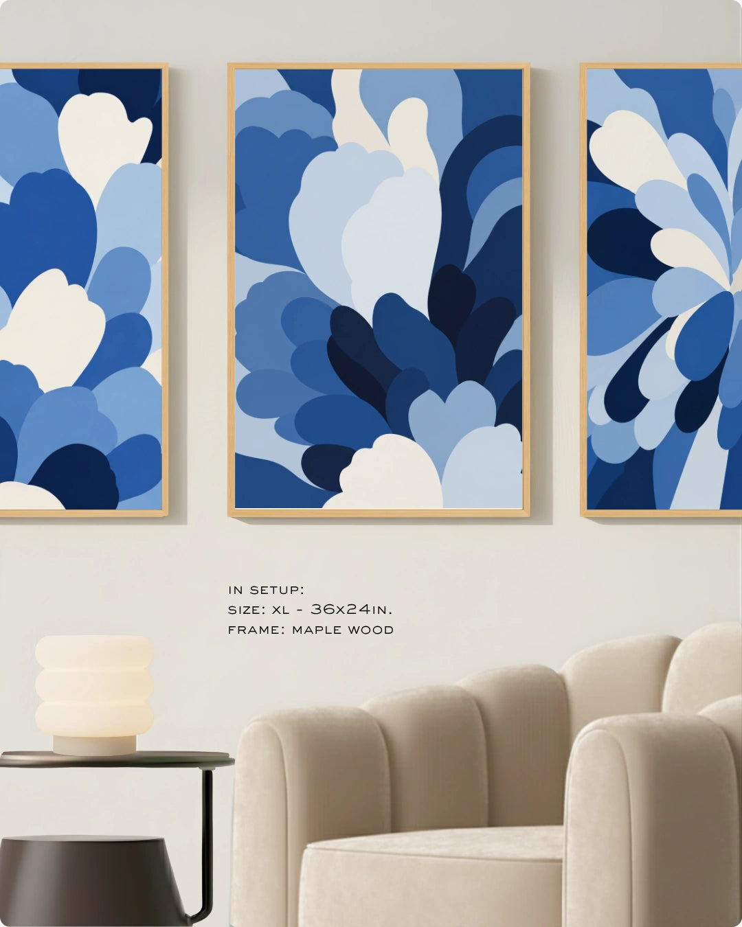 Three framed abstract blue floral wall art prints displayed above a beige sofa in a living room setting. The center print is fully visible, with parts of the left and right prints visible at the edges.