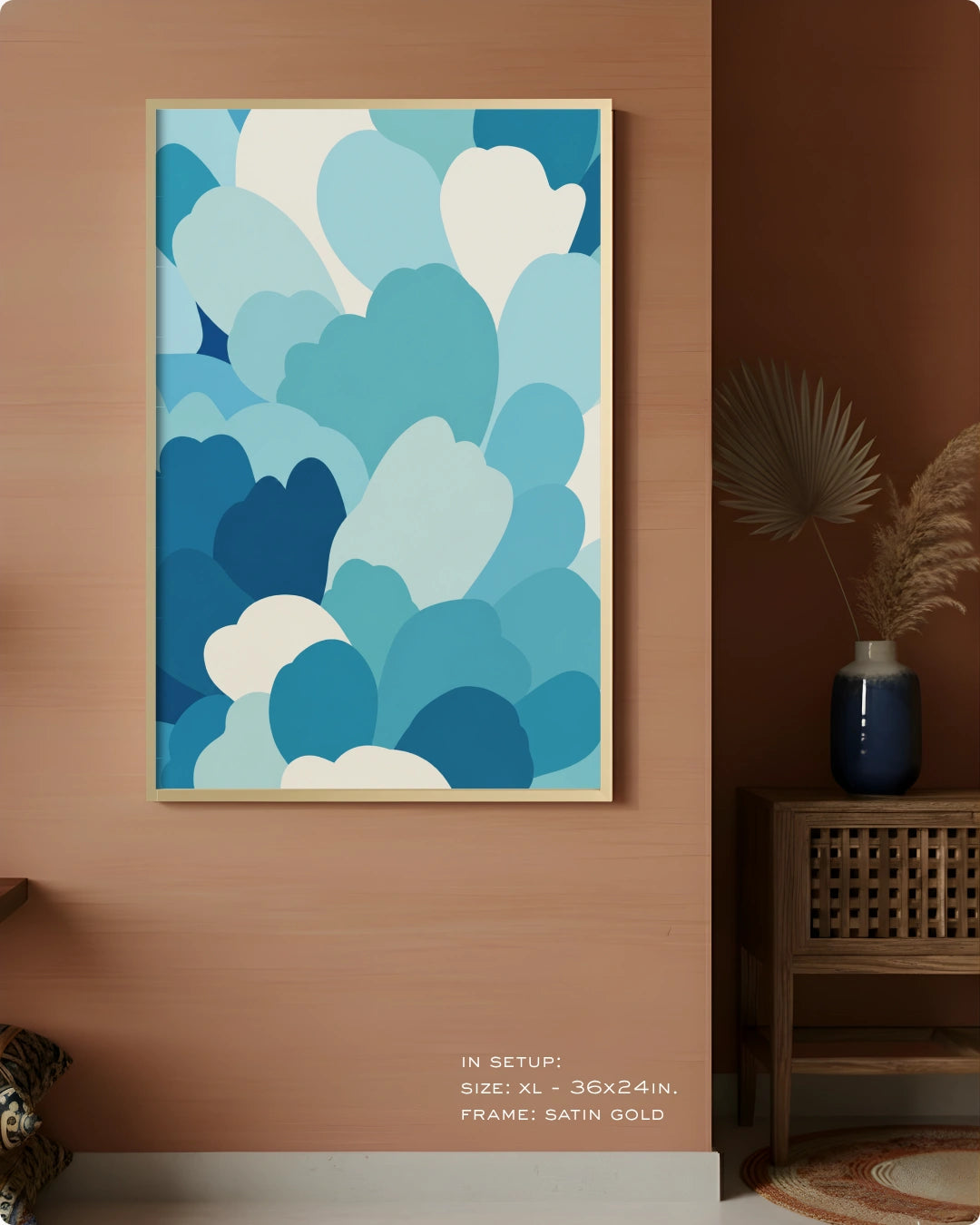 A framed wall art print featuring an abstract pattern of layered cloud-like shapes in shades of blue and white, hung on a warm terracotta-colored wall in a styled interior setting.