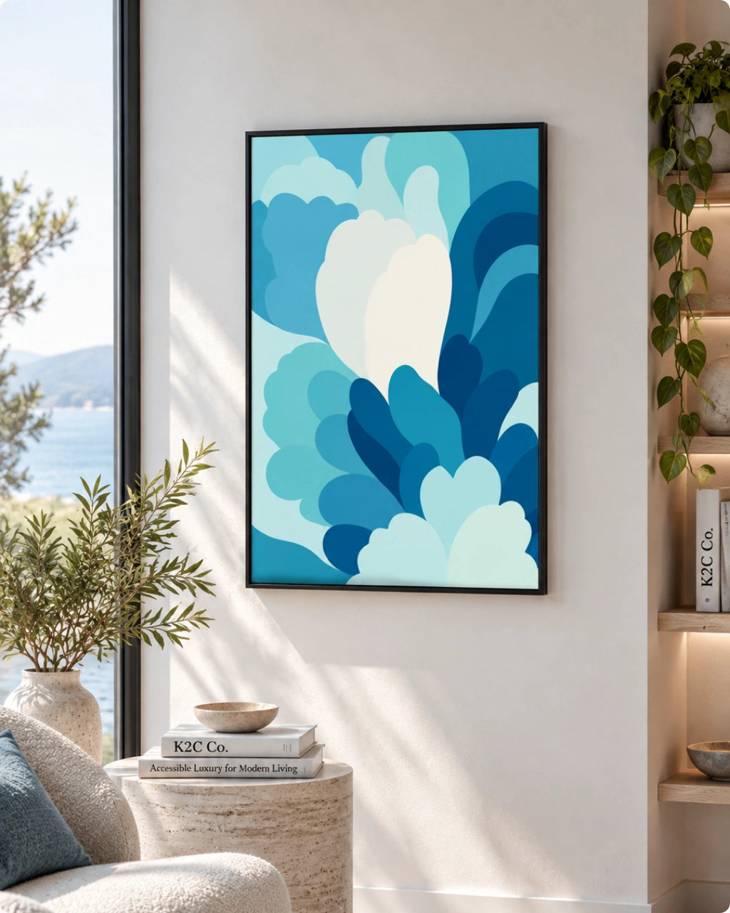 A framed abstract art print featuring layered blue and white cloud-like shapes, displayed on a light beige wall in a modern living room setting with a window, plants, and a side table.