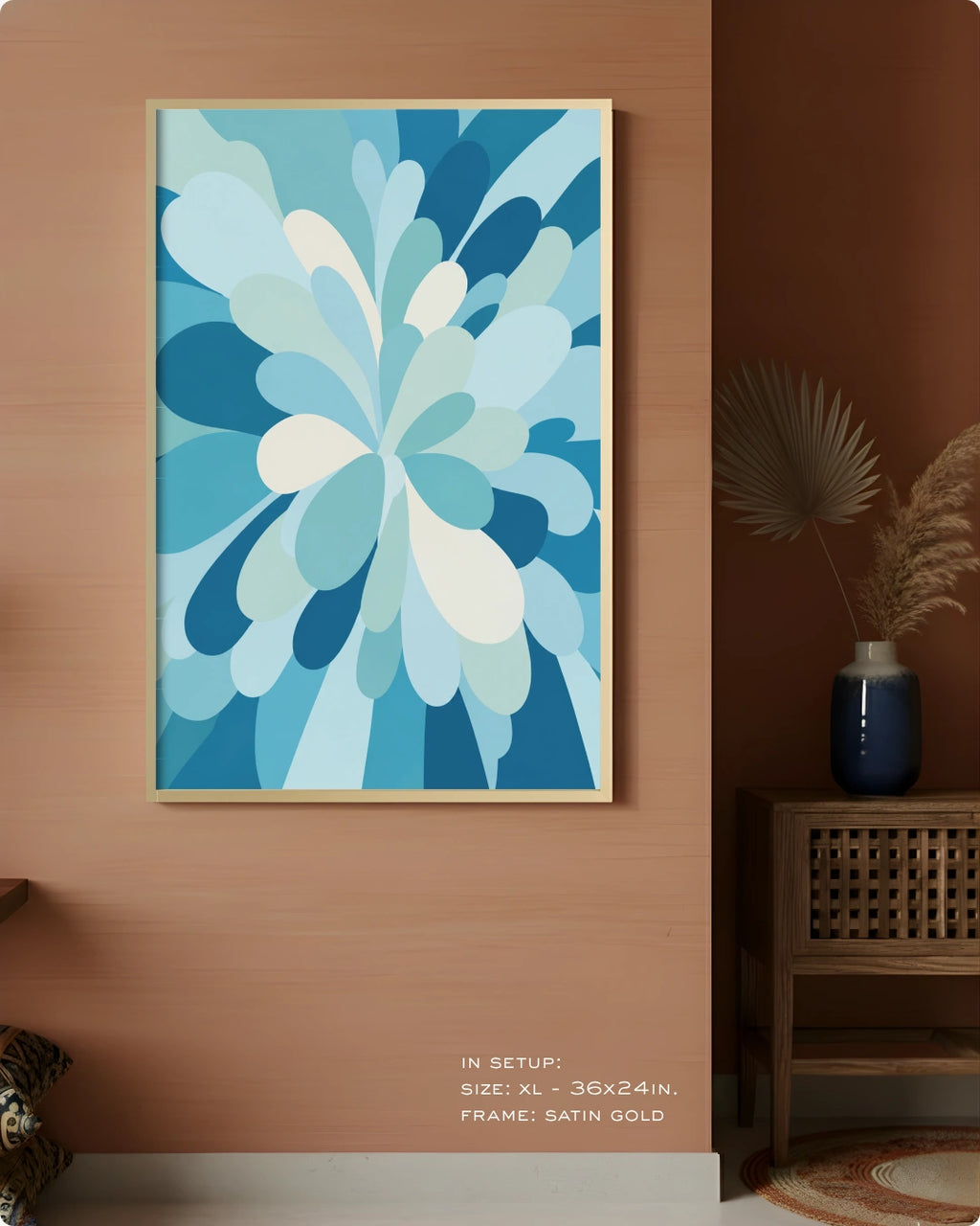A framed abstract floral art print in shades of blue, teal, and white, displayed on a warm terracotta wall in a styled interior setting with a side table and vase.