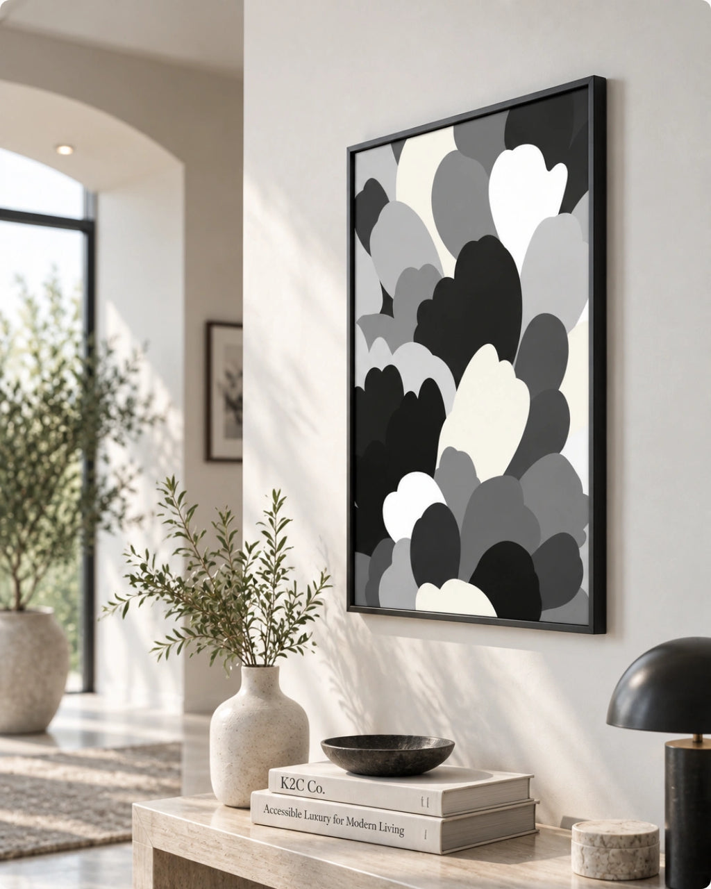 Framed wall art with an abstract black, gray, and white cloud-like pattern hanging on a light wall in a modern interior setting.