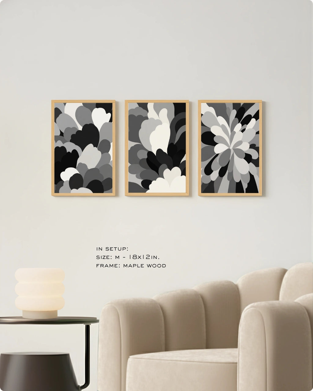 Three framed abstract floral wall art prints in black, gray, and white are displayed on a light gray wall above a beige armchair, with small text noting size and maple wood frames.