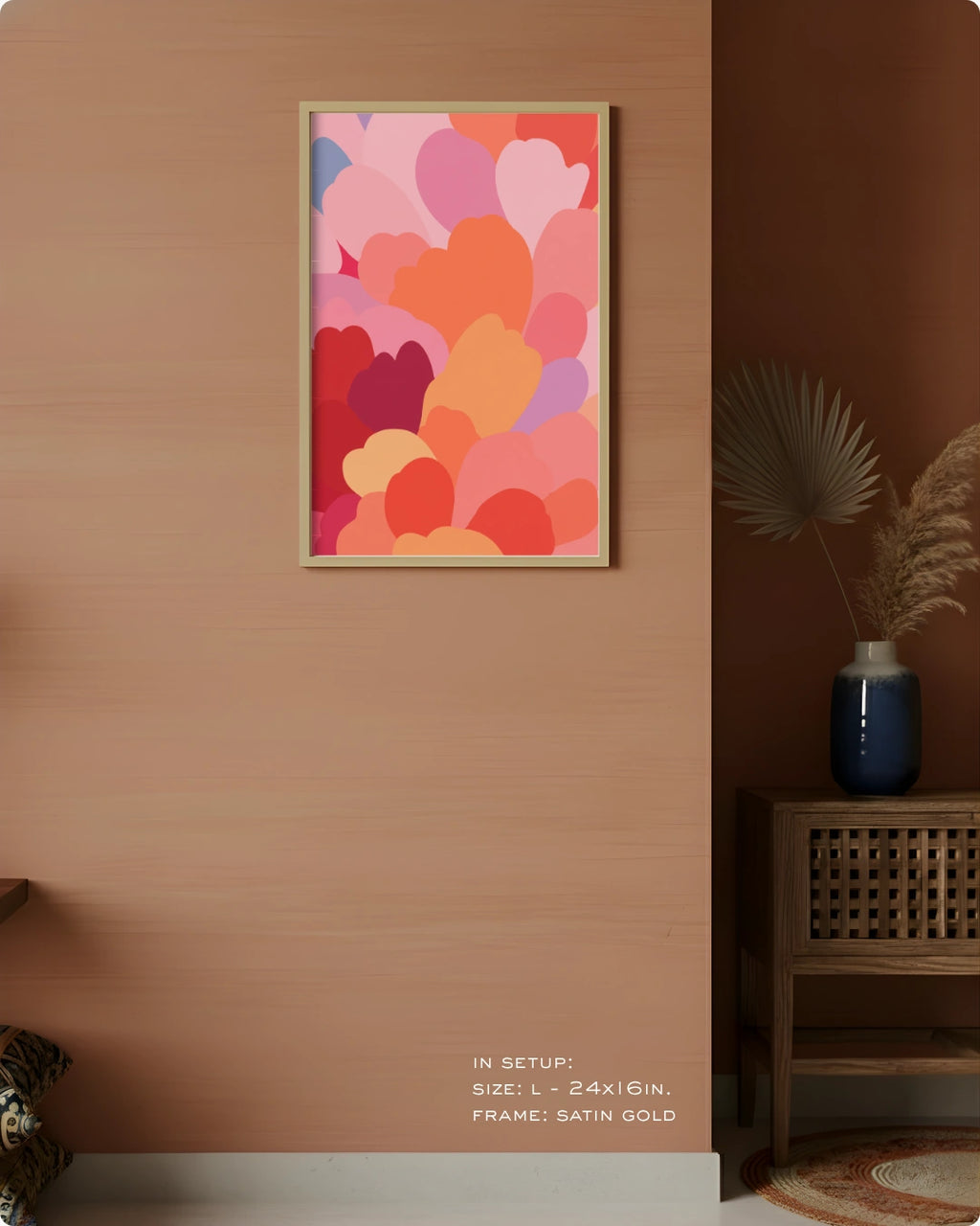 A framed wall art print featuring overlapping heart shapes in pink, red, orange, and purple tones, displayed on a warm peach wall in a styled interior setting with a side table and vase.
