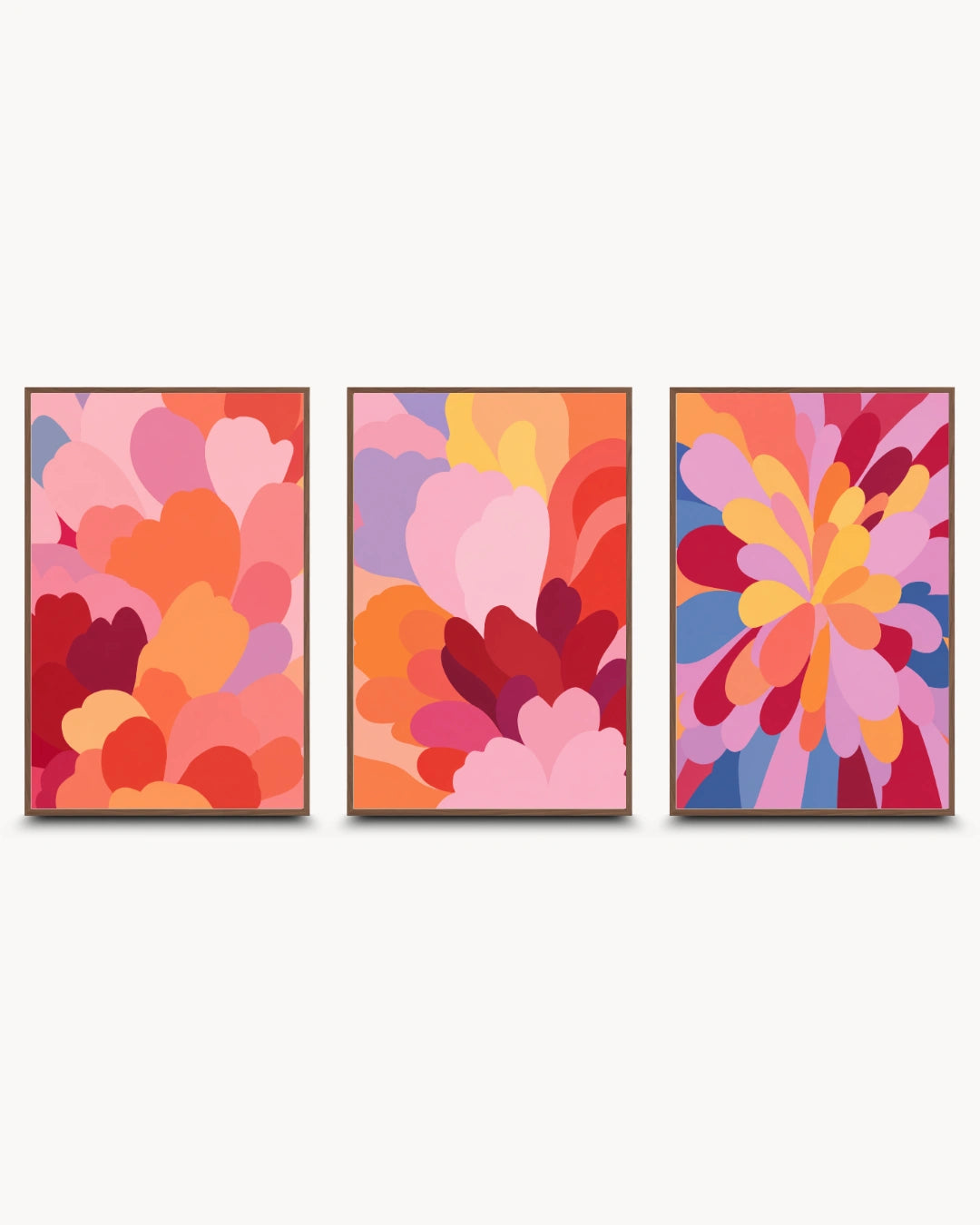 A set of three framed abstract wall art prints with colorful floral and petal-like patterns in pink, orange, red, purple, and blue, displayed side by side on a light gray background.