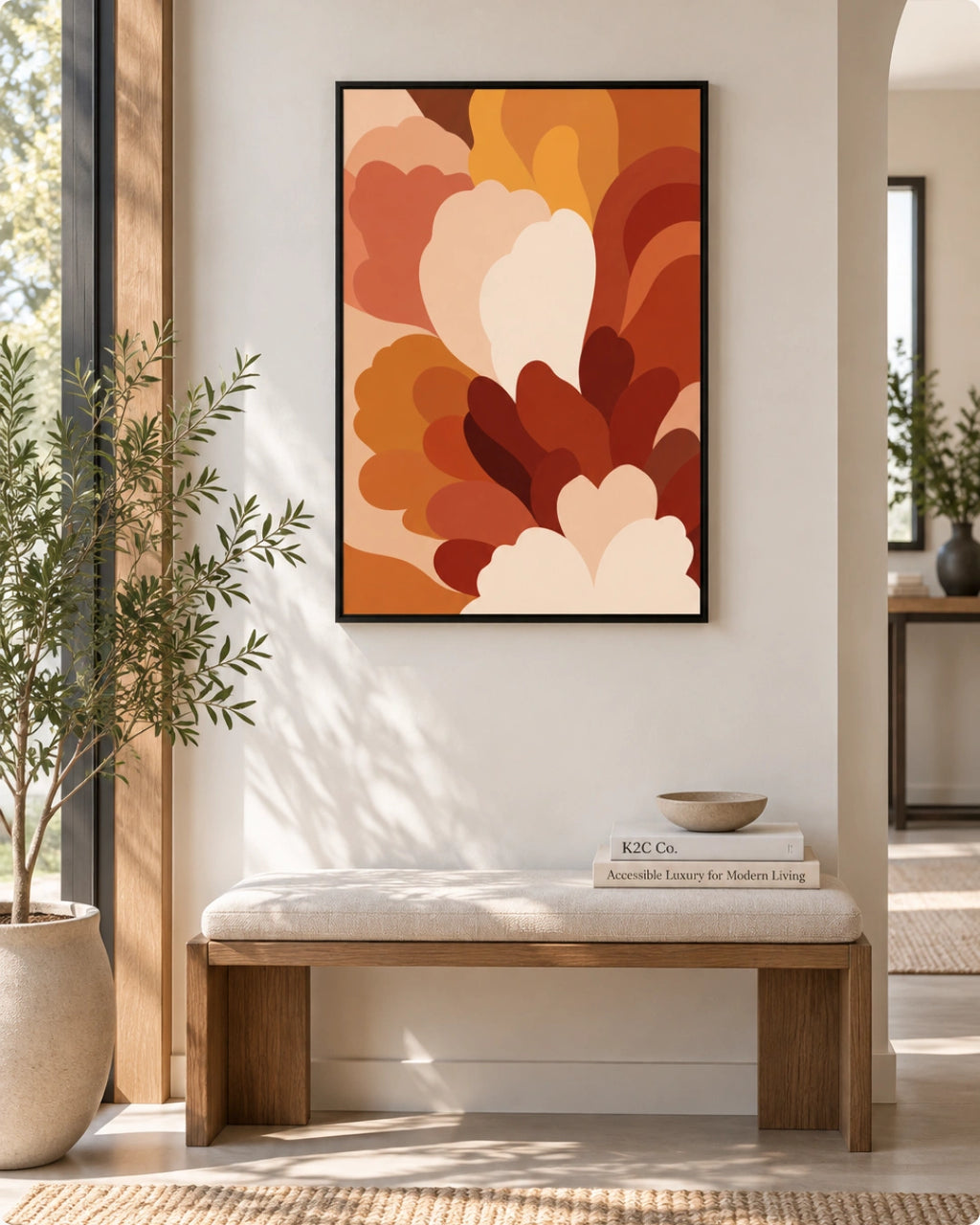 A framed abstract floral wall art print in warm autumn colors hangs above a wooden bench with a cream cushion in a bright, modern entryway.