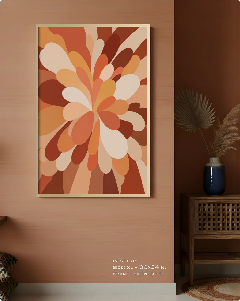 A framed abstract floral wall art print hangs on a warm peach-brown wall in a styled interior. The artwork features layered petal-like shapes in terracotta, rust, tan, cream, and orange tones.